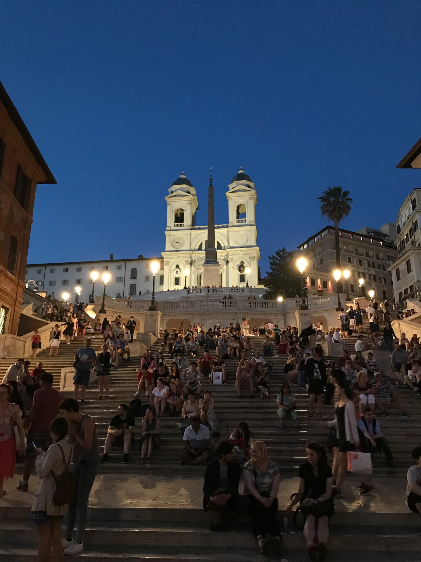 The Spanish Steps at blue hour with lamps lit and the church glowing above.