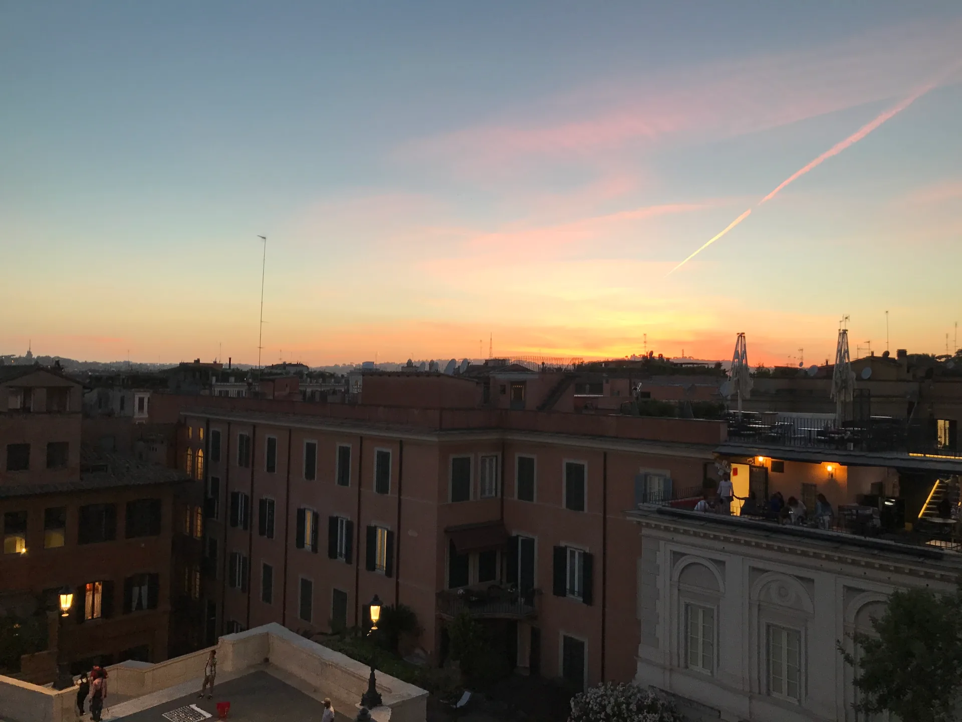 Orange and pink sunset over the rooftops of Rome from the Spanish Steps.