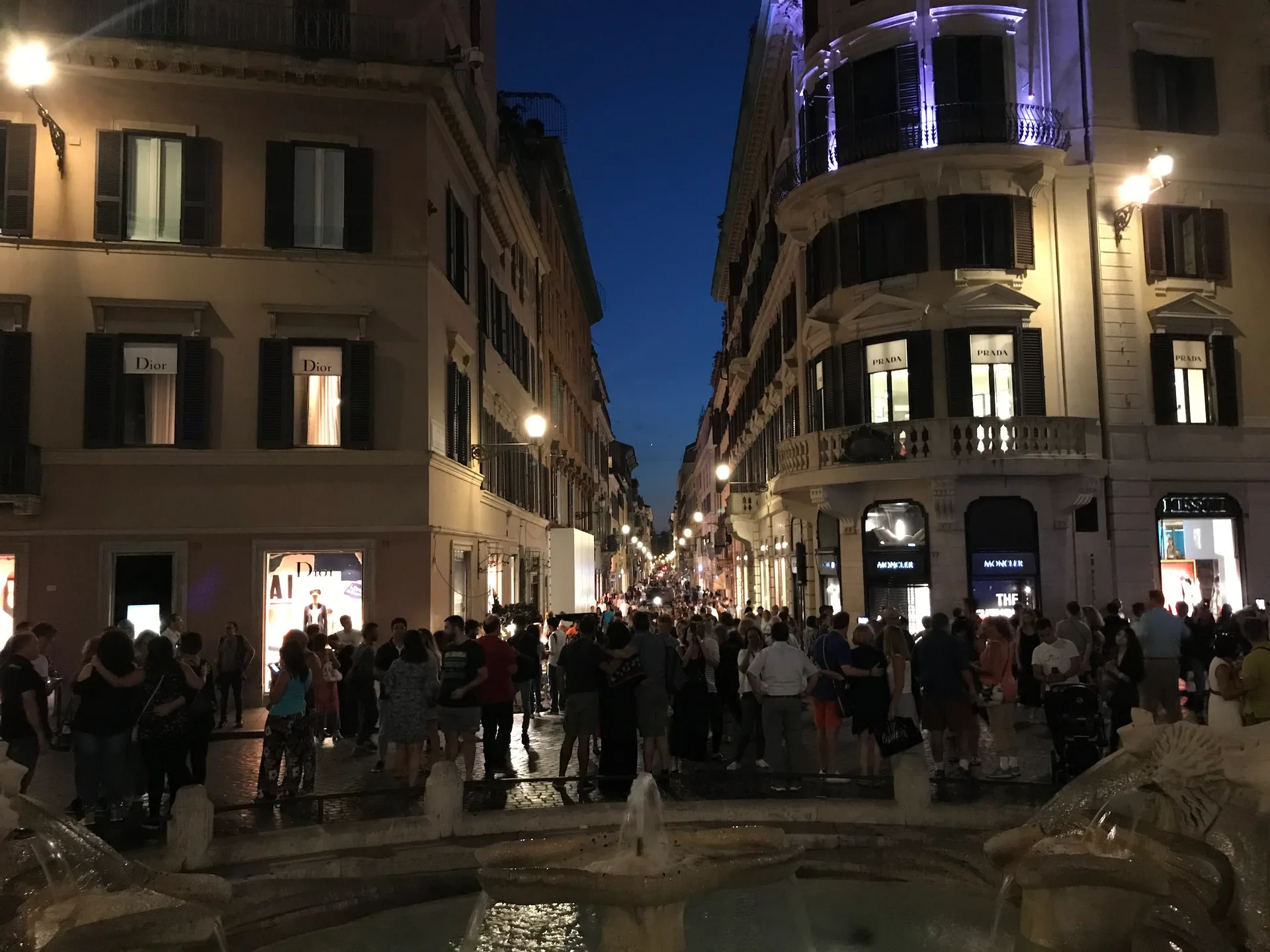 Crowds by the Barcaccia with Via dei Condotti lit at night, Piazza di Spagna.
