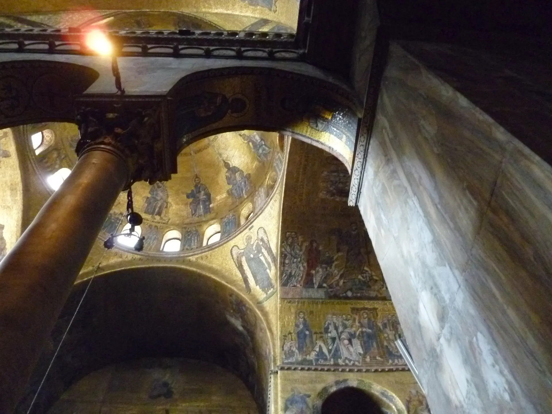 Interior of St Mark's Basilica with a marble column and a shaft of light across the mosaics