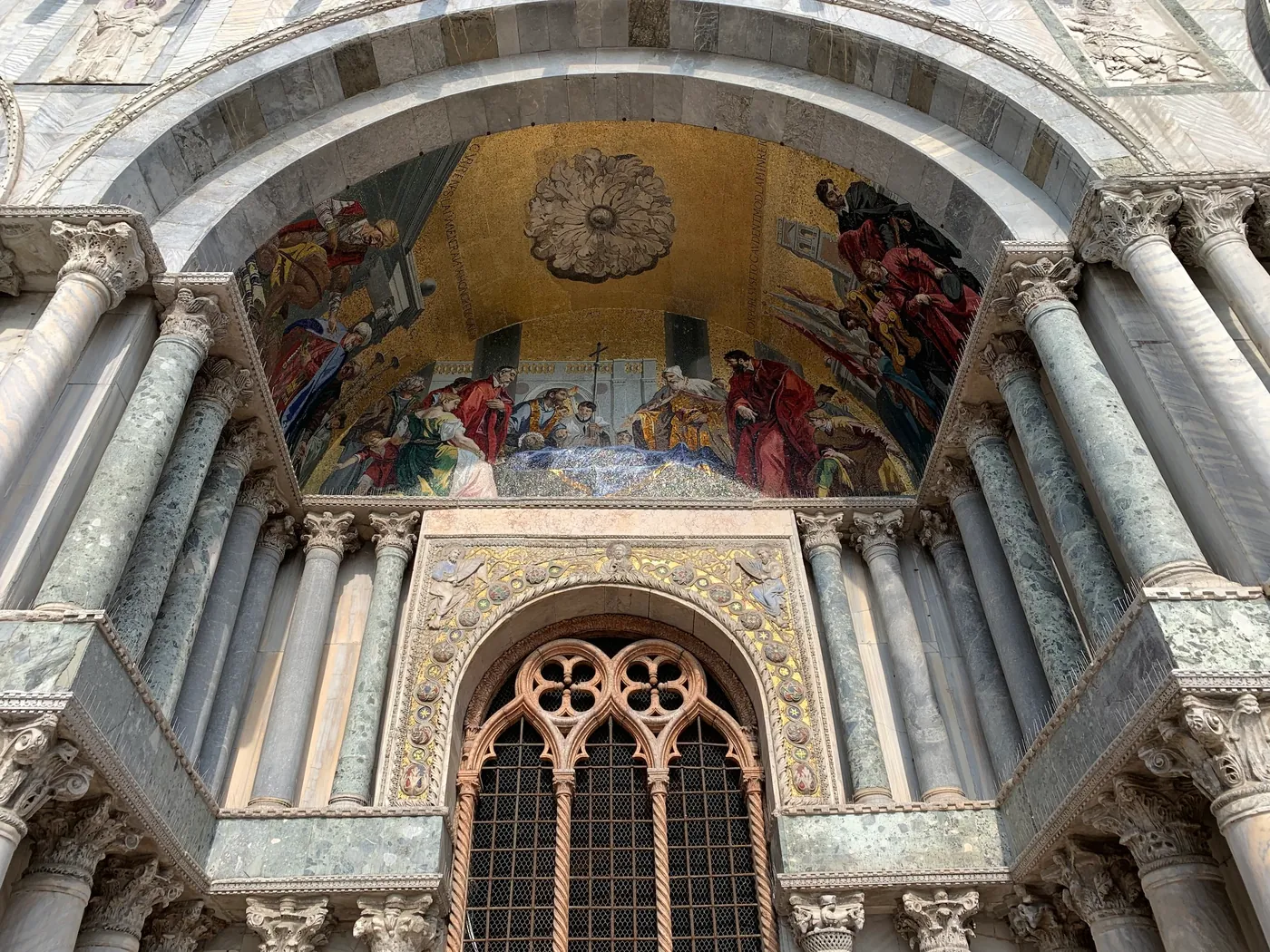 Mosaic-filled arch over a portal of St Mark's Basilica with a gothic window below