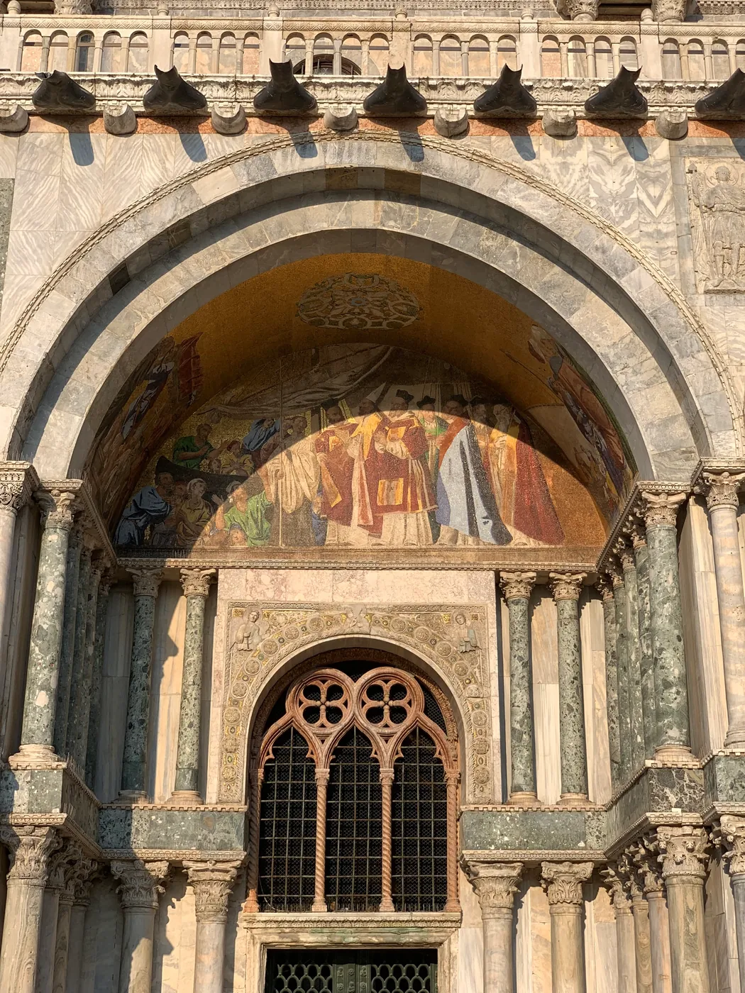 Gilded mosaic and rose window over a side portal of St Mark's Basilica