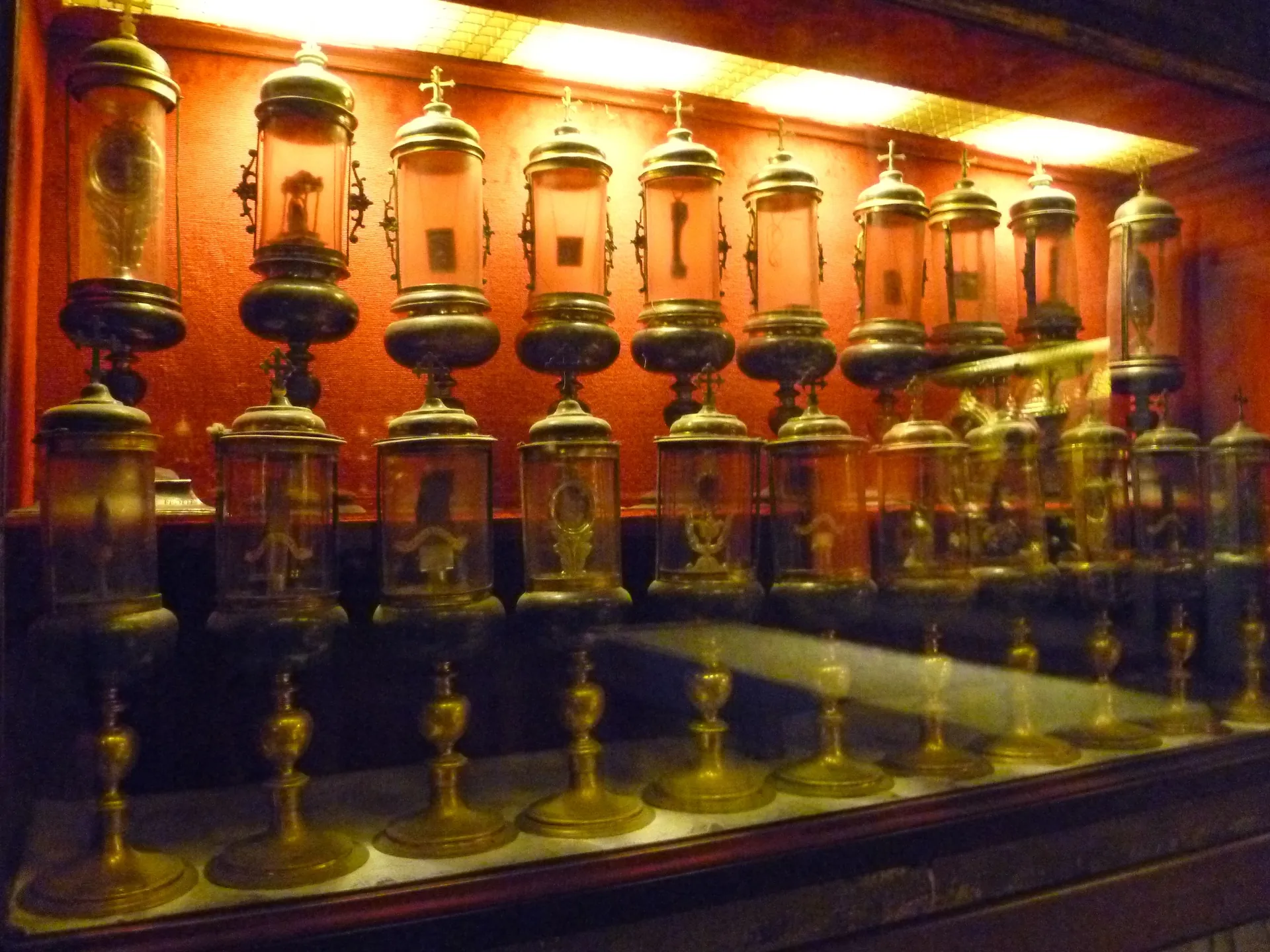 Row of golden reliquaries in the Treasury of St Mark's Basilica against a red backdrop