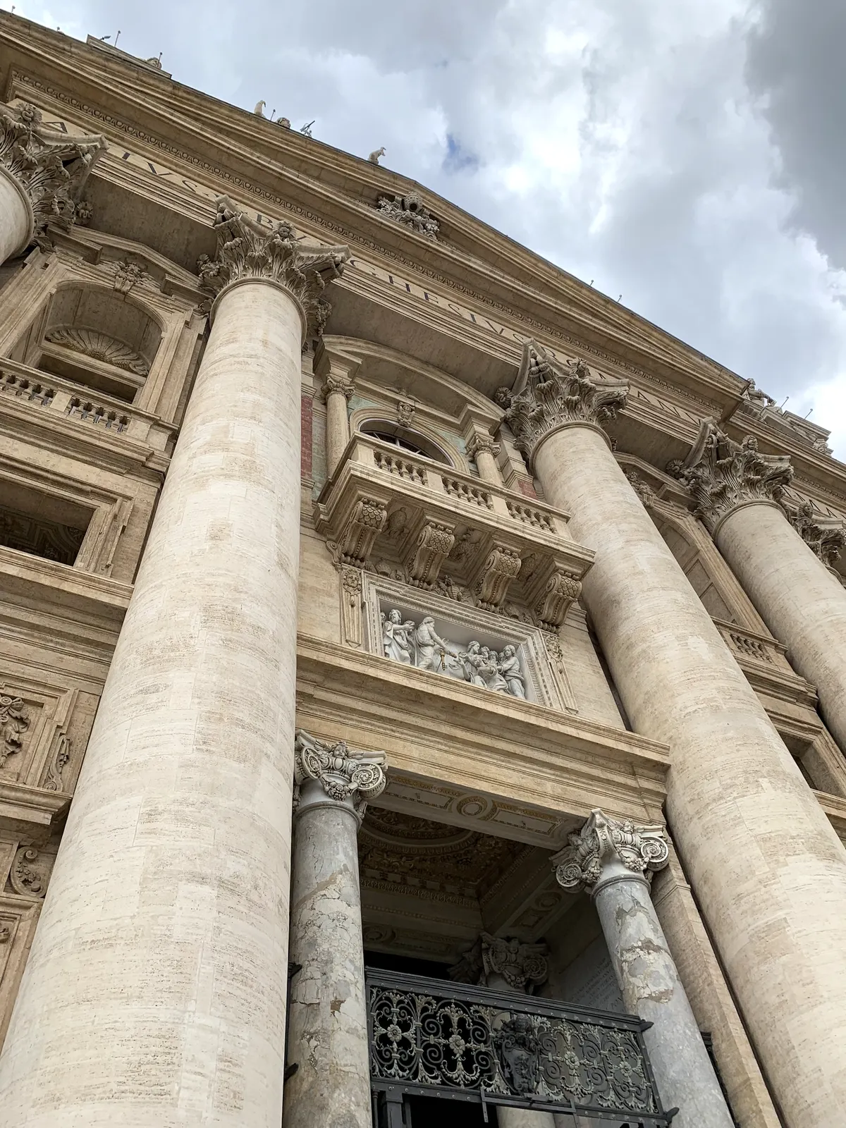 The colossal columns of St. Peter's facade seen from below against clouds