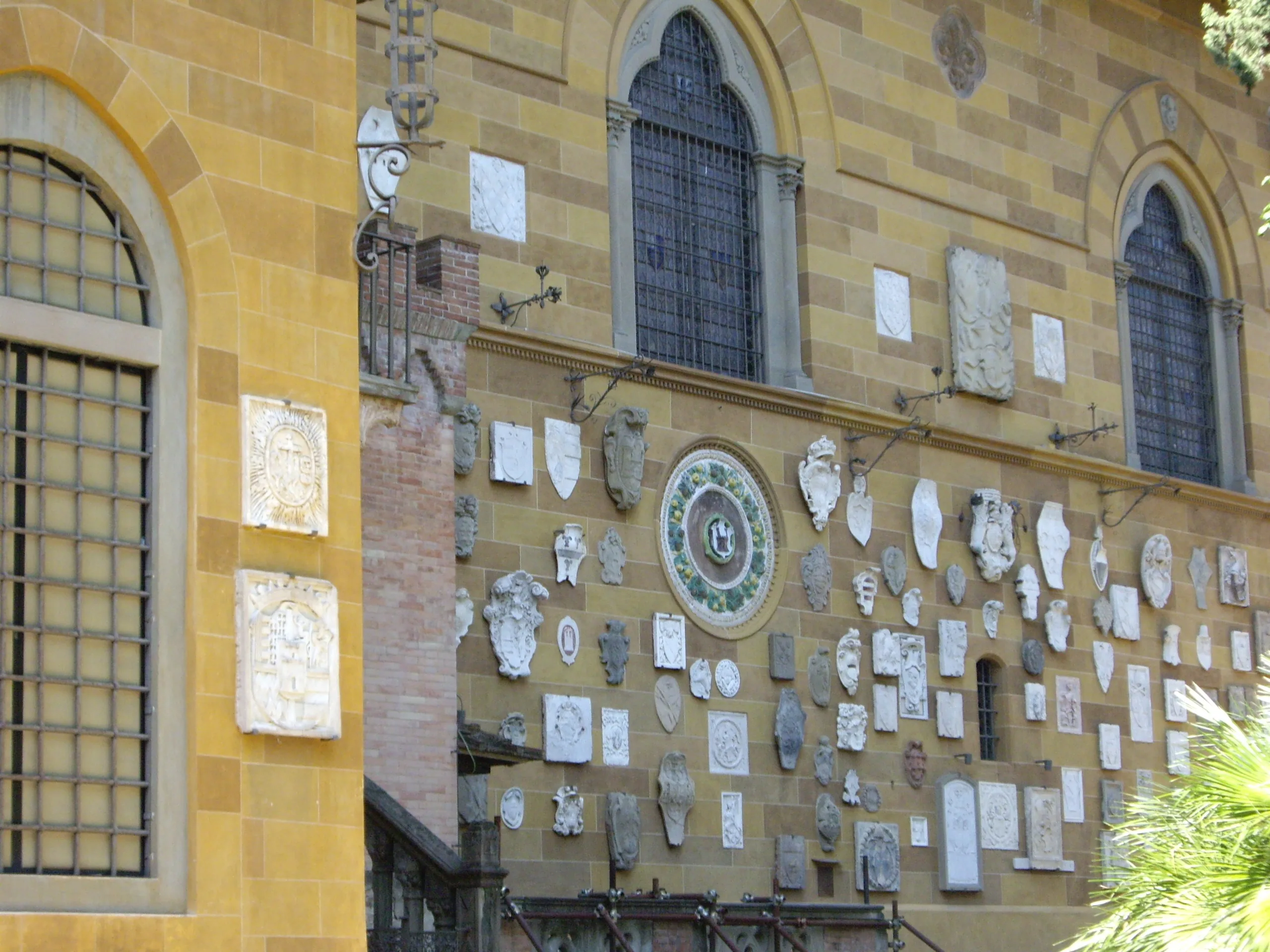 The long wall of the Villa Stibbert, hung with marble roundels, carved plaques and heraldic shields