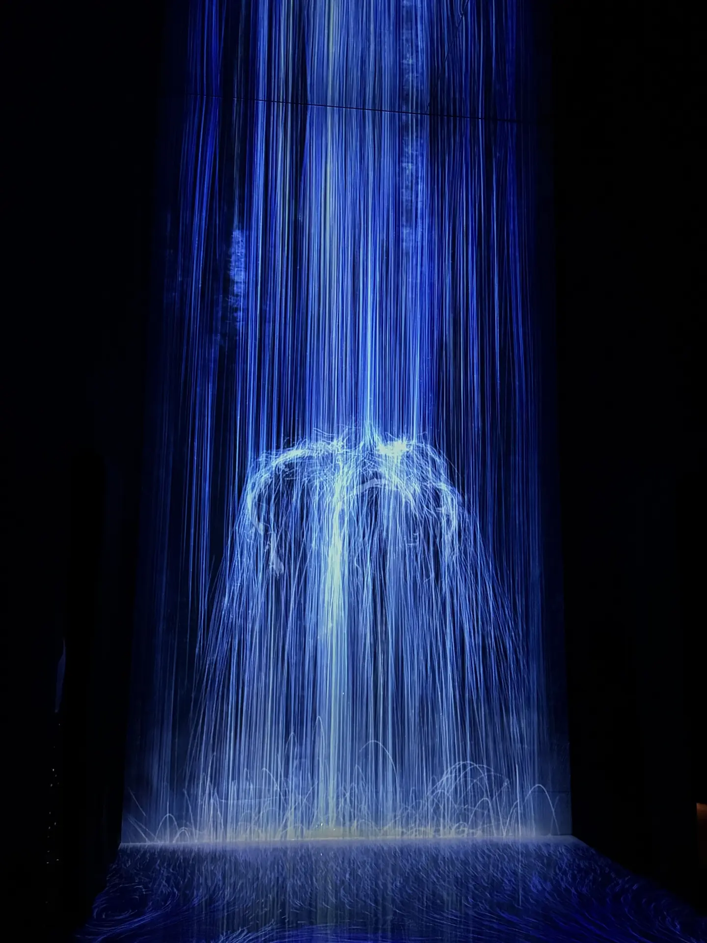 Projected waterfall of light in a dark teamLab installation, Tokyo
