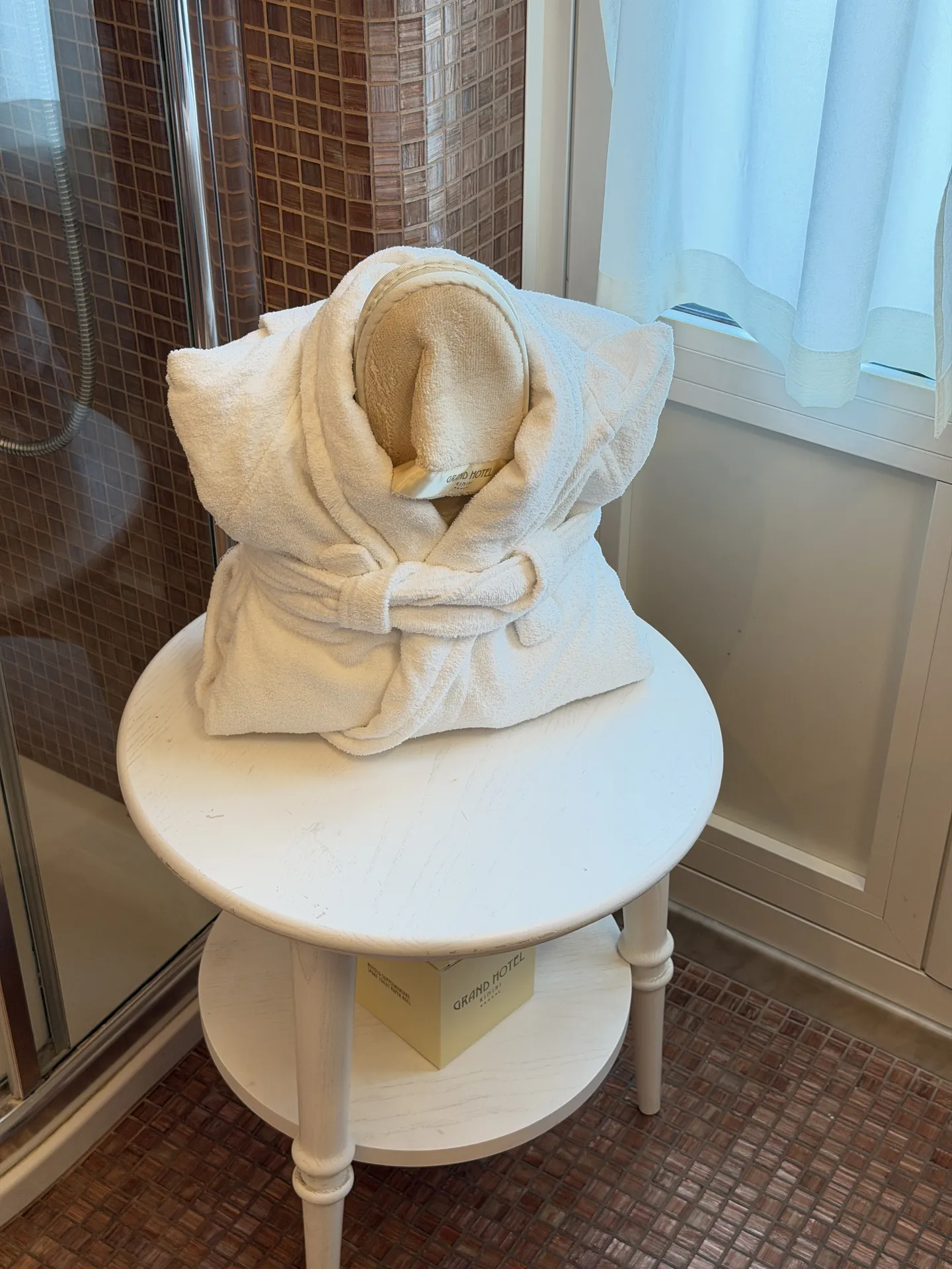 Folded bathrobe on a painted stool in a hotel bathroom