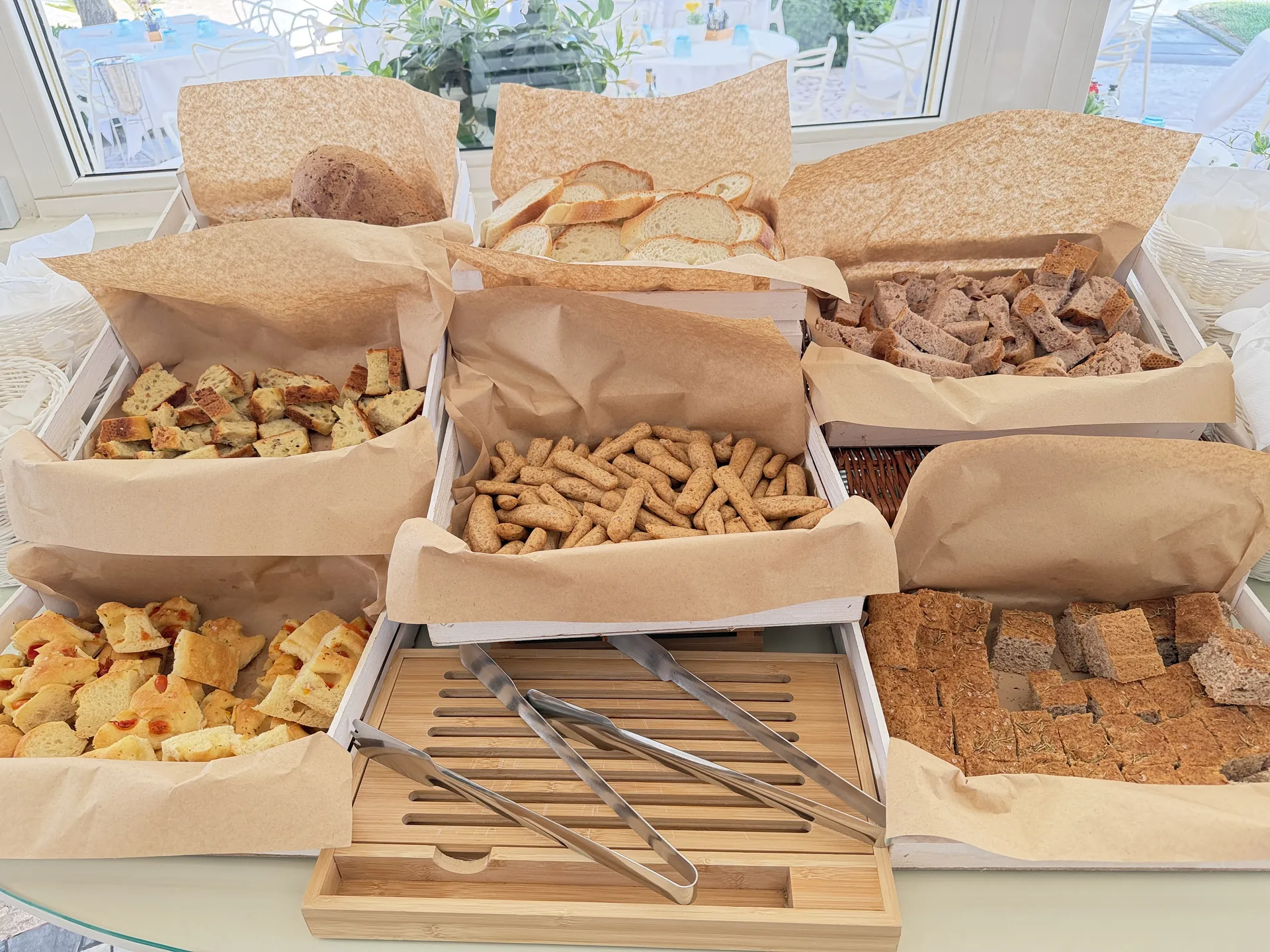 Bread, breadsticks and focaccia in paper-lined baskets with the beach beyond