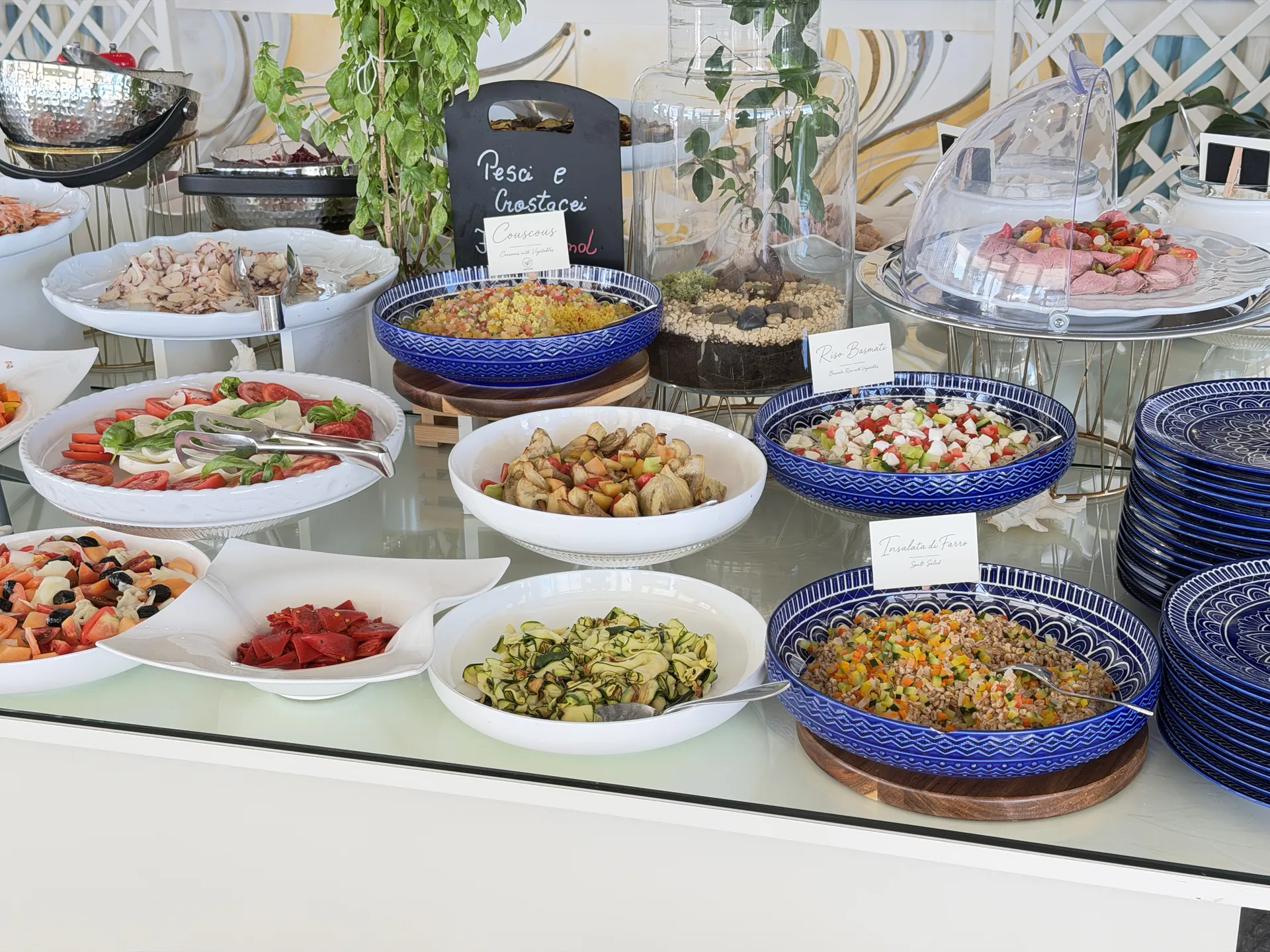 Couscous, farro salad and caprese in blue bowls under a Pesce e Crostacei board