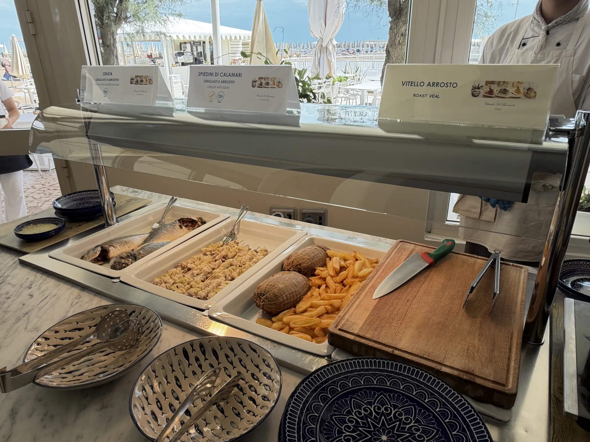Grilled bream, squid skewers and roast veal on the hot counter of the beach buffet