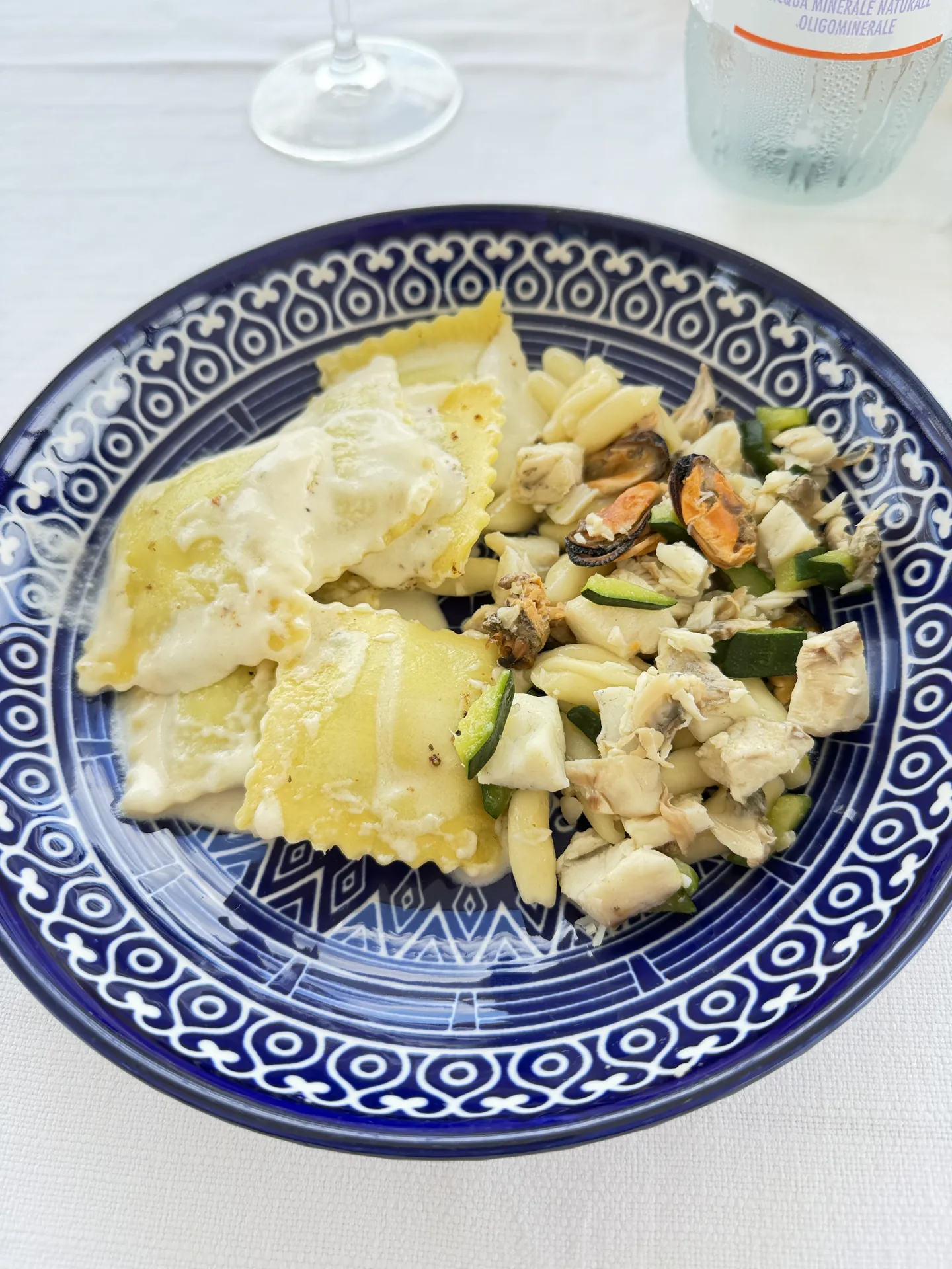 Ravioli with clams and courgette on a blue and white plate