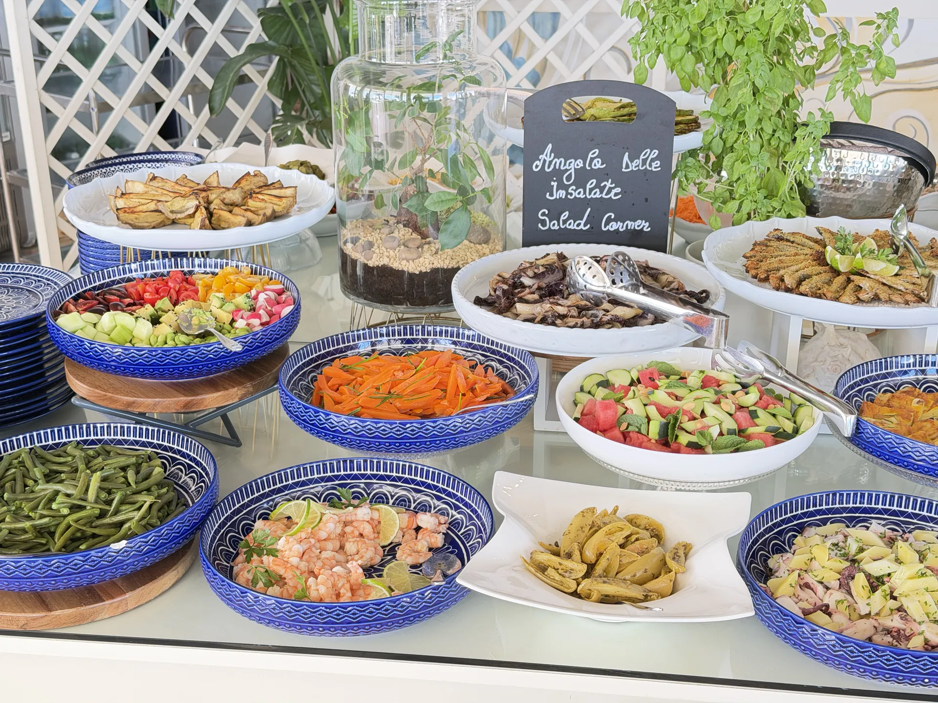 The salad corner of the beach buffet, blue bowls of beans, carrots, prawns and octopus