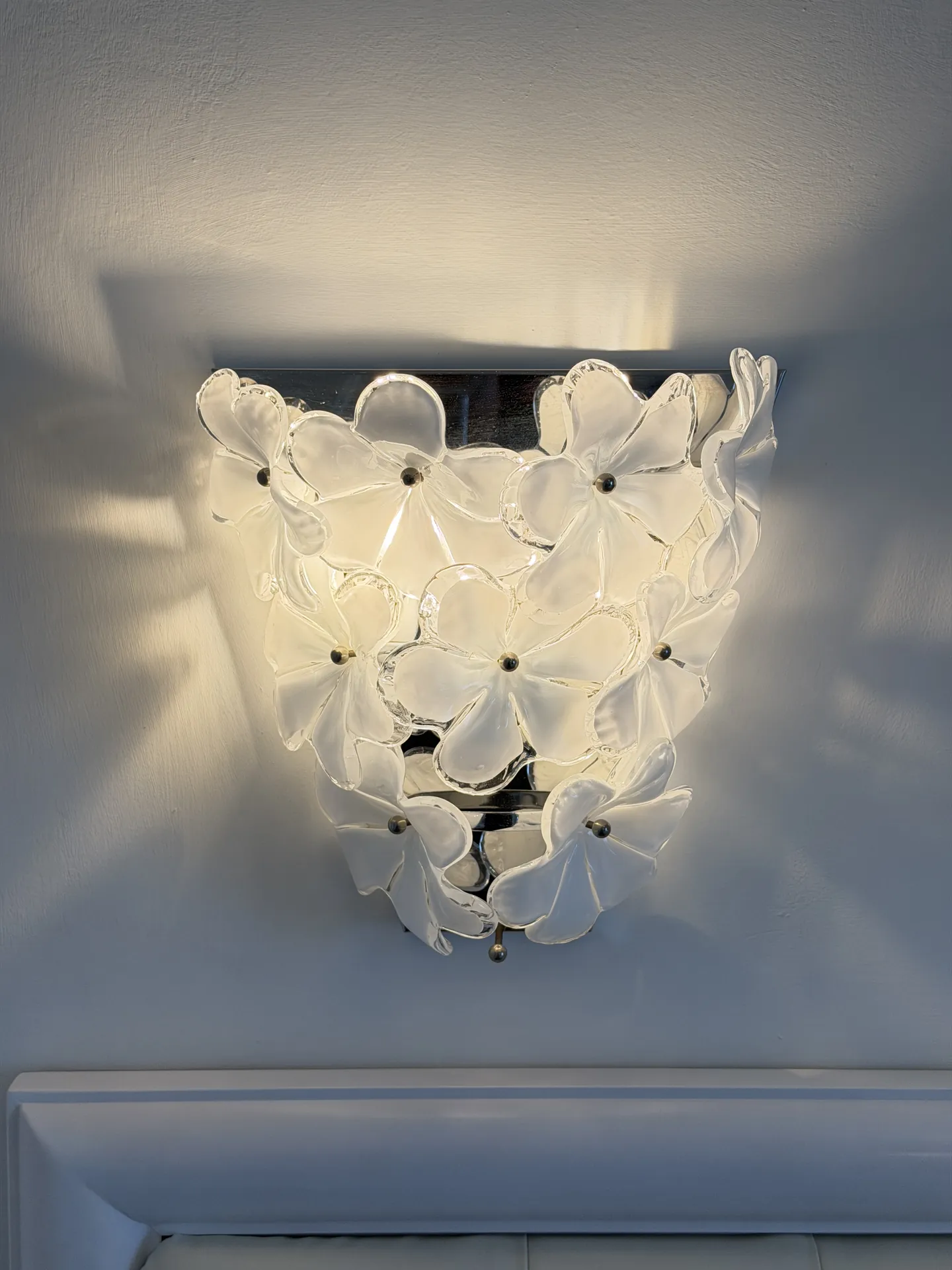 White Murano glass flower sconce on a hotel room wall