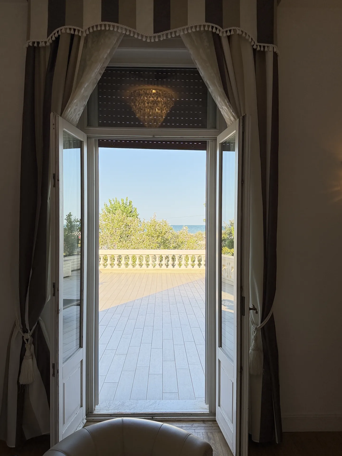 Open French door from a hotel room onto its private sea-facing terrace