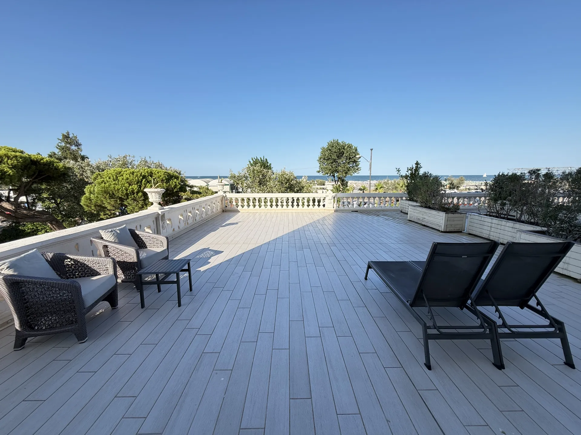 A wide private terrace with loungers and seating, the balustrade and the Adriatic beyond