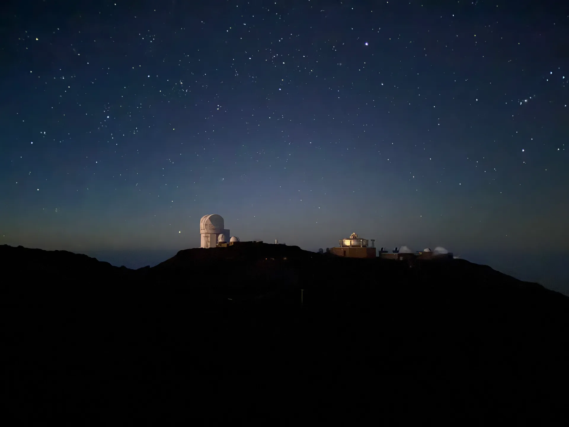 Star filled night sky above the silhouetted domes of Haleakala Observatory