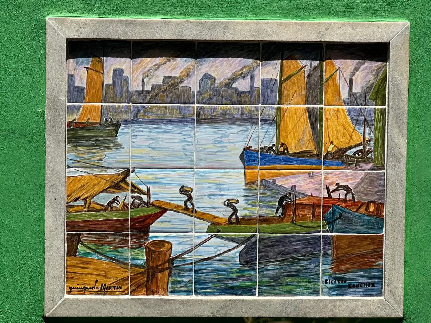 A ceramic tile mural of dockworkers on a green wall in La Boca.