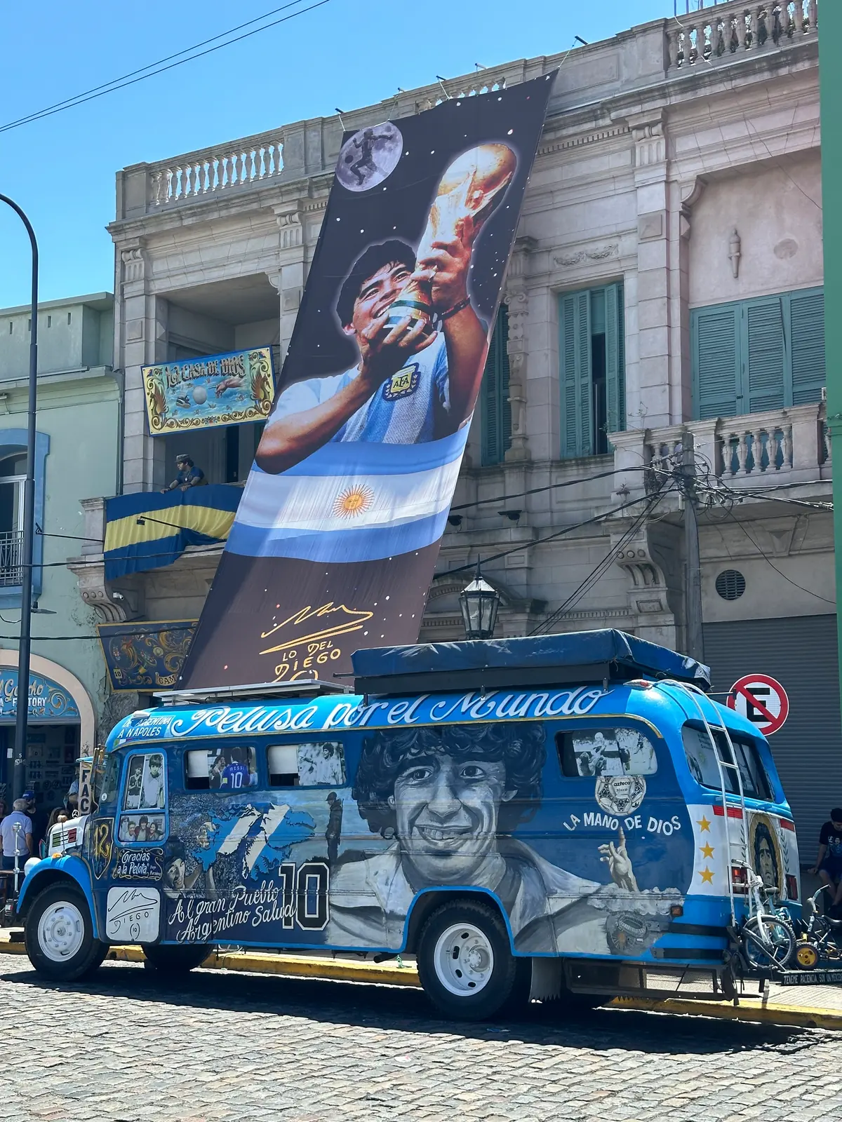 A bus painted with murals and Argentine colours parked in a La Boca street.