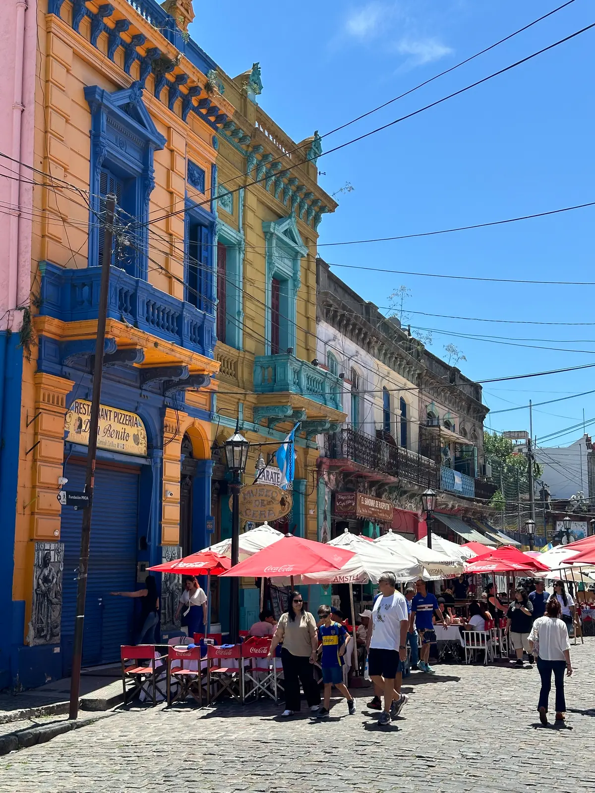 Painted houses above a market square with red umbrellas at Caminito.