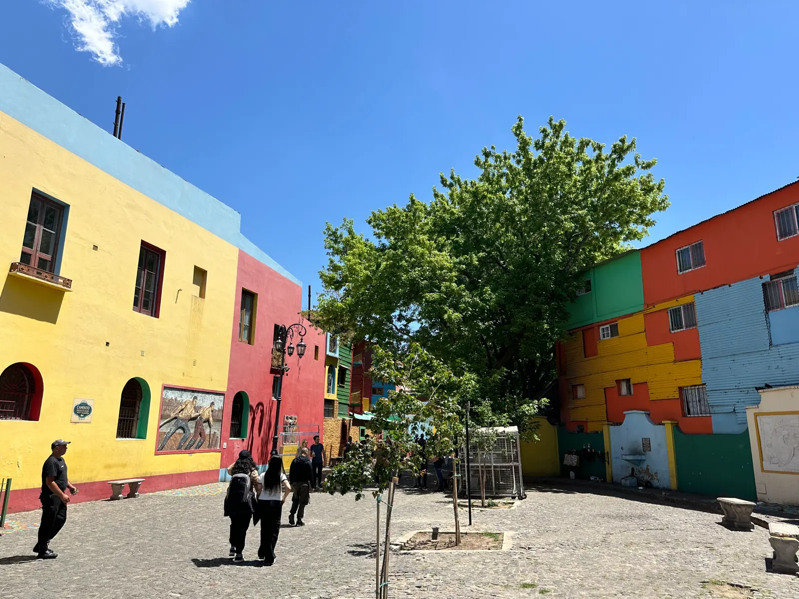 Painted corrugated block facades in blue, yellow and red under deep blue sky.