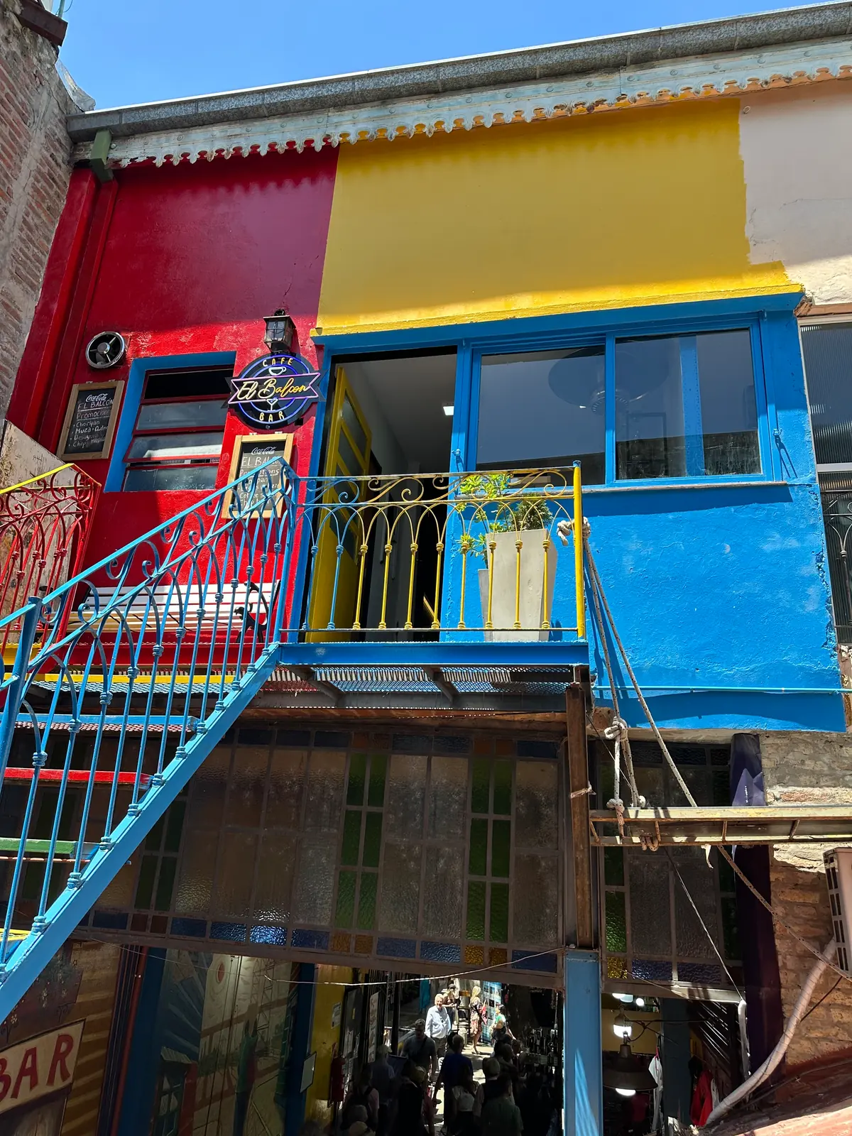A painted external staircase across a red, yellow and blue facade in La Boca.