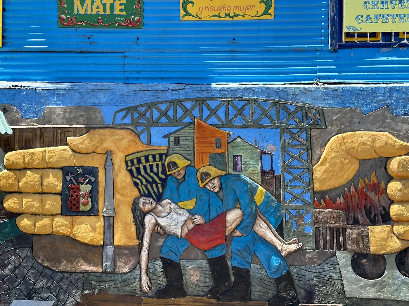 A painted relief mural of workers carrying an injured man with furnaces behind.
