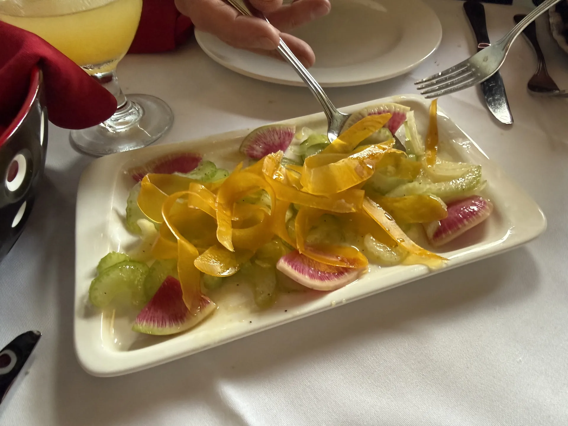 A salad of shaved bottarga and celery on a rectangular plate.