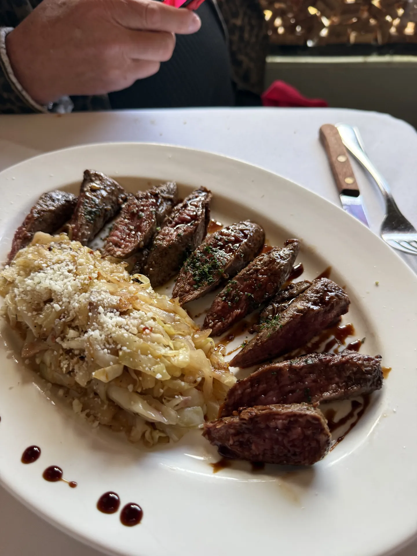 Seared lamb tenderloin, sliced, with a saba drizzle on a white plate.