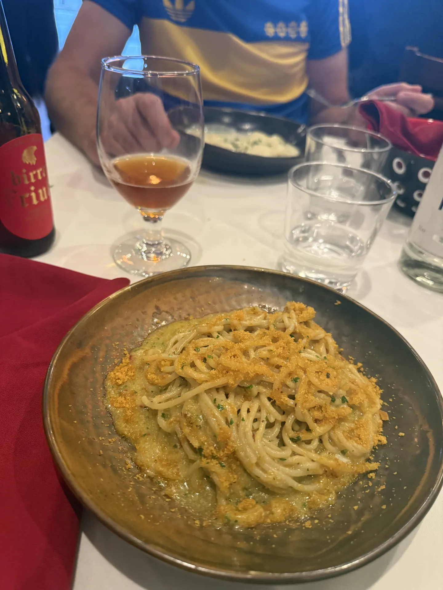 Fresh spaghetti with garlic, oil, and grated bottarga in a dark bowl.
