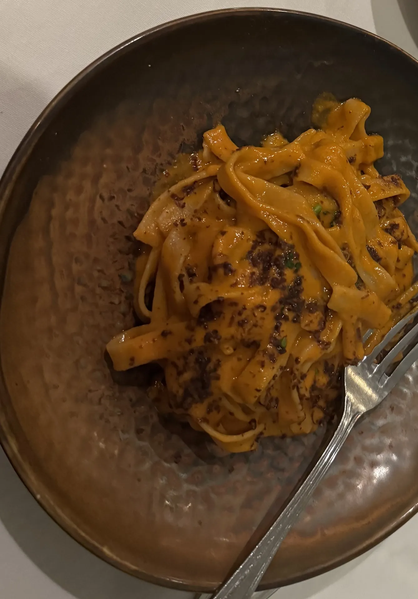 Fettuccine in a creamy sea urchin sauce with grated cured tuna heart in a metal bowl.