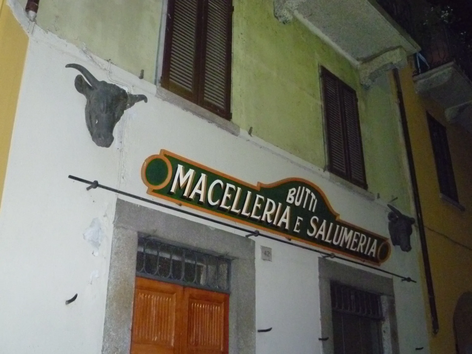 A butcher shopfront in Bellagio with a bull's head sculpture mounted above the sign.