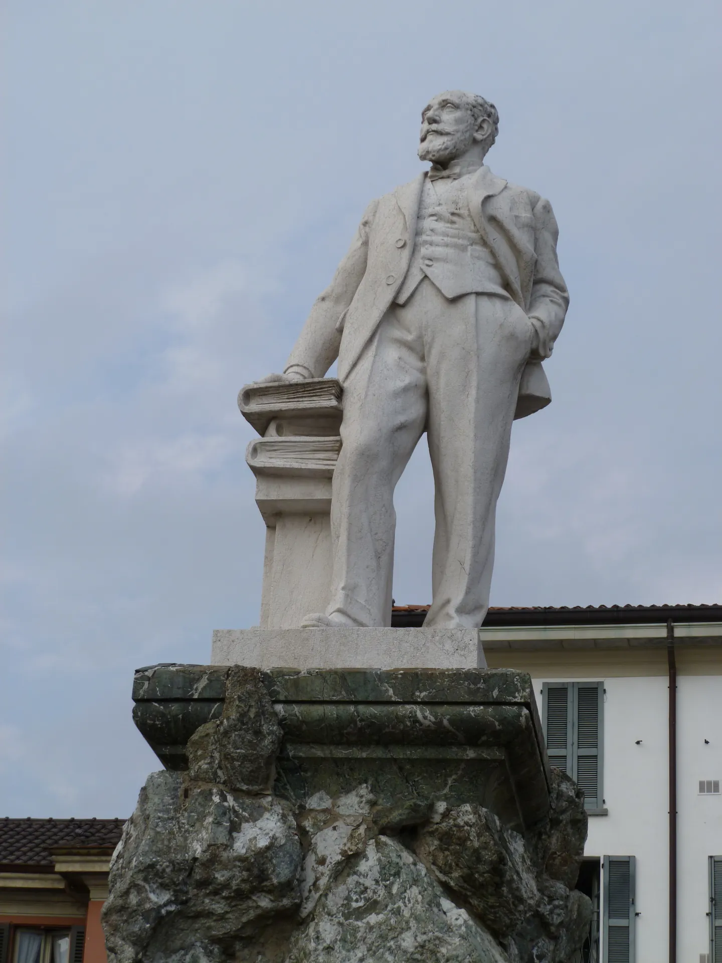 A marble statue of Mario Cermenati on a rough rock plinth in Piazza Cermenati, Lecco.