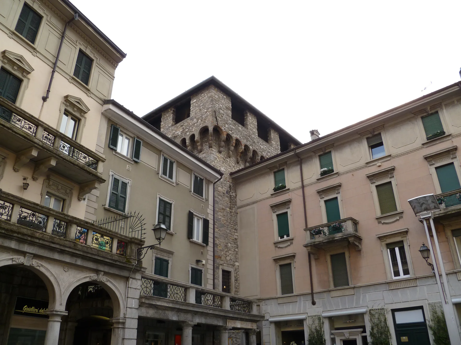 The medieval brick Torre Viscontea rising between painted facades in Lecco.