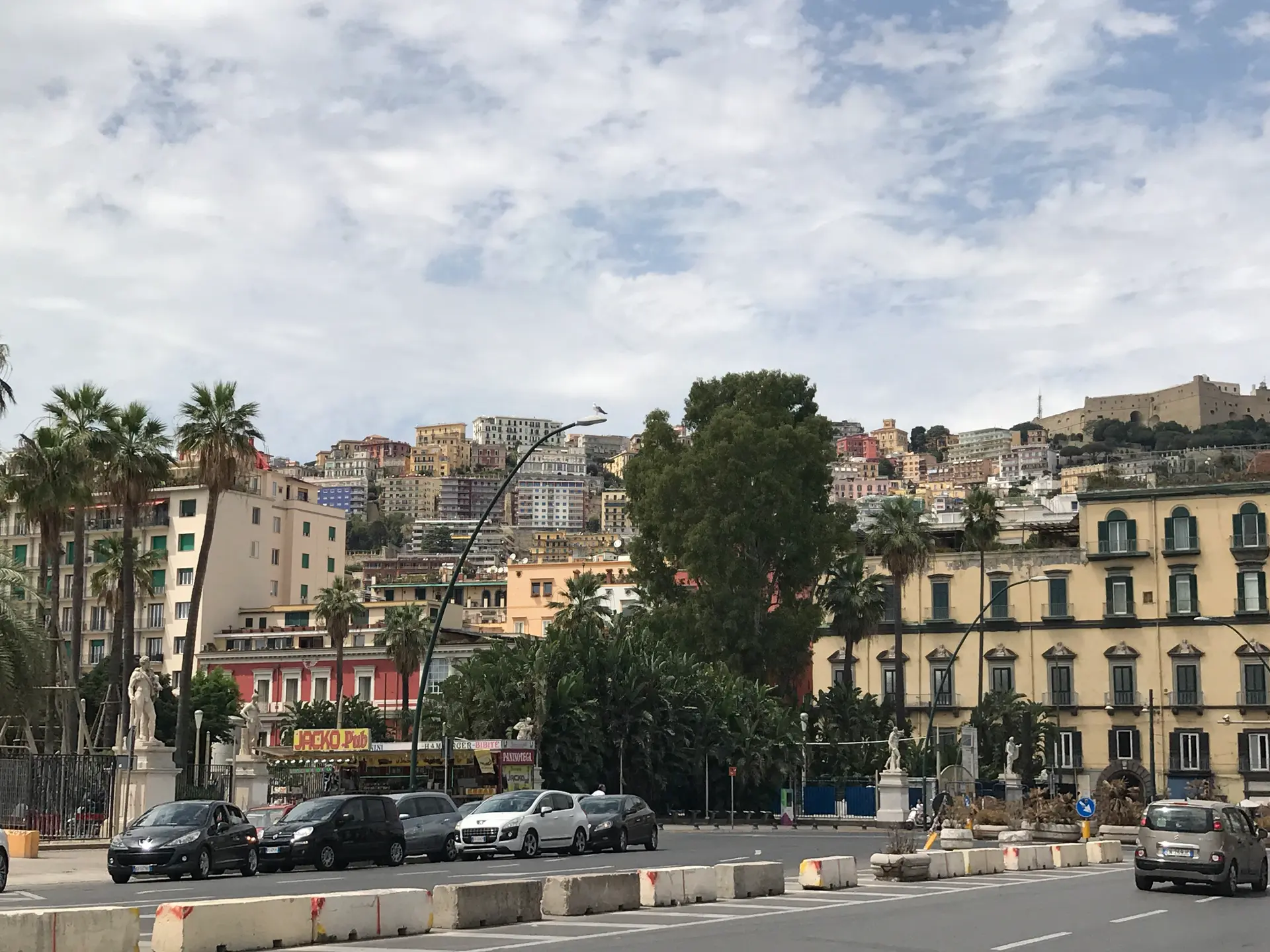Via Partenope in Naples with palms, hotel buildings and traffic along the seafront.
