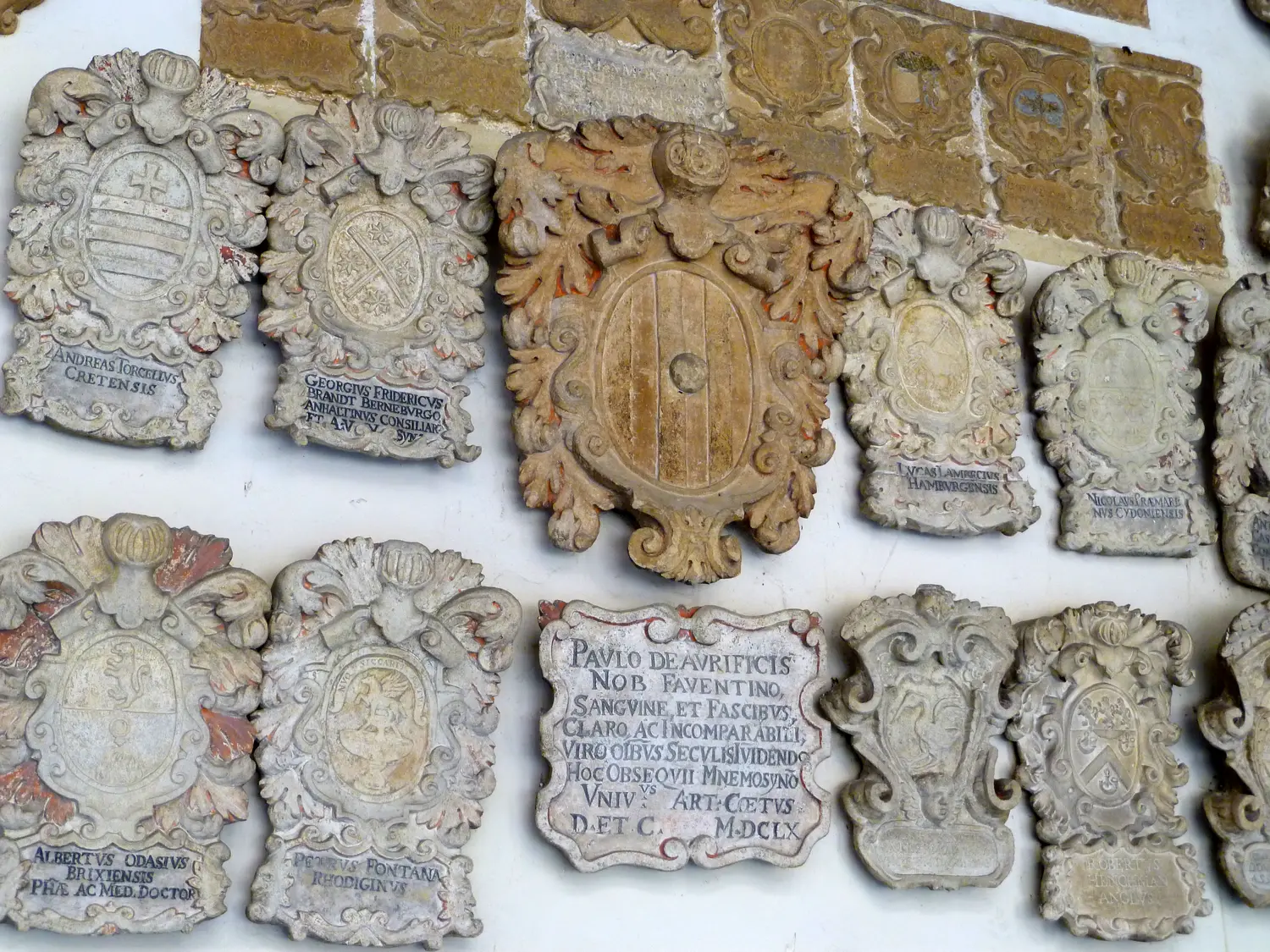 Carved stone coats of arms of former students covering a wall in the courtyard of Palazzo del Bo