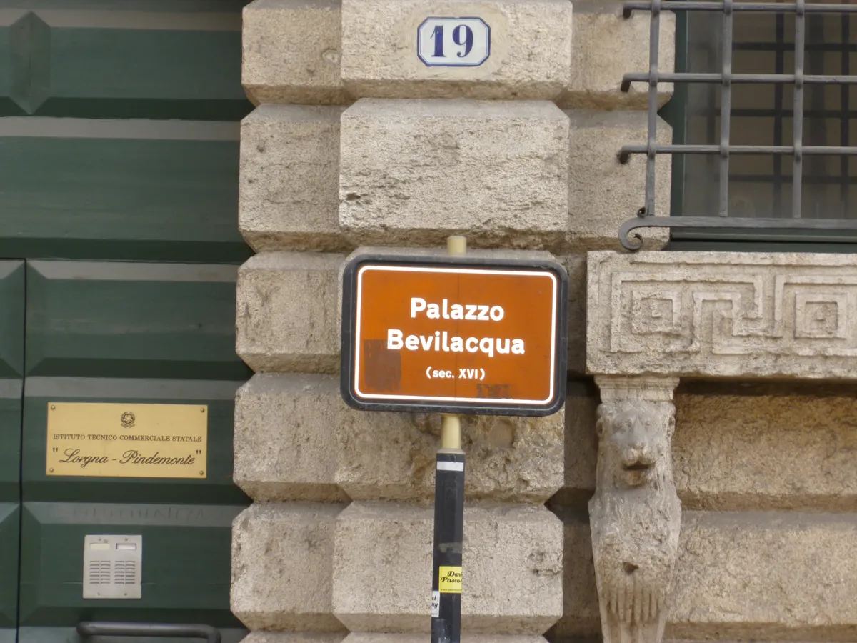 The rusticated corner of Palazzo Bevilacqua in Verona with its carved Greek key frieze and street sign