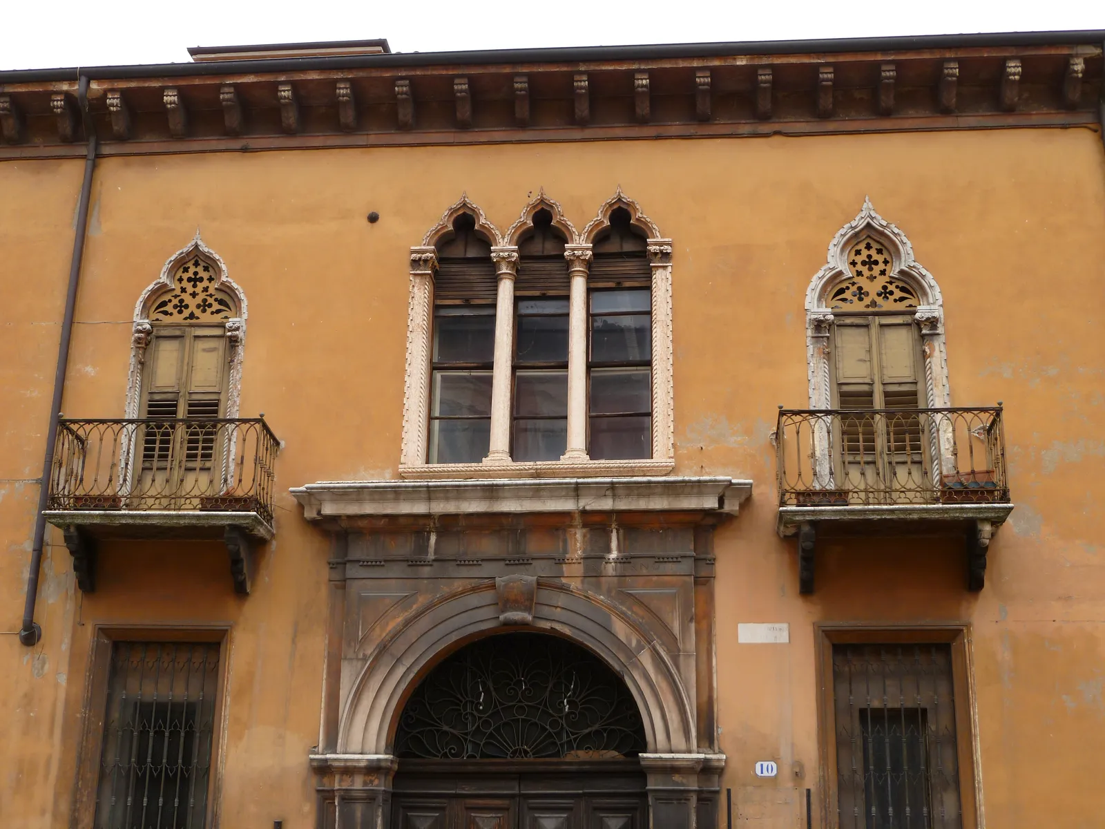 A Venetian Gothic facade in the old town of Verona, trilobate windows and carved balconies above a stone portal