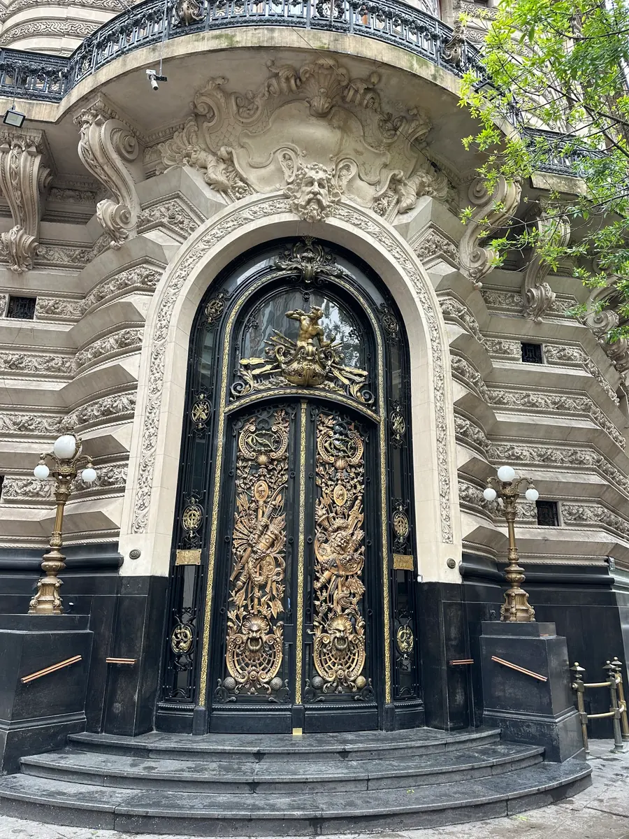 An ornate carved stone portal with gilded bronze doors at Palacio Barolo.