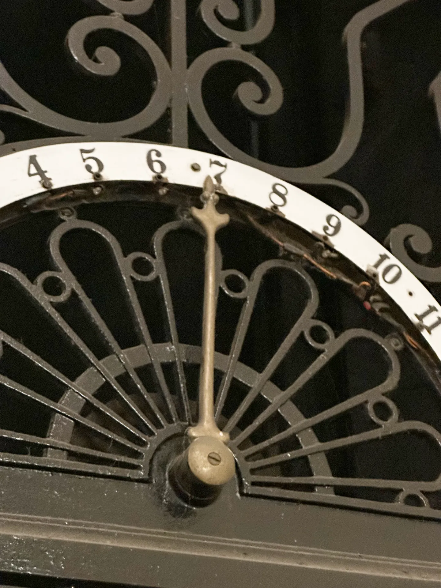 A brass semicircular floor indicator dial with a pointer above a lift.