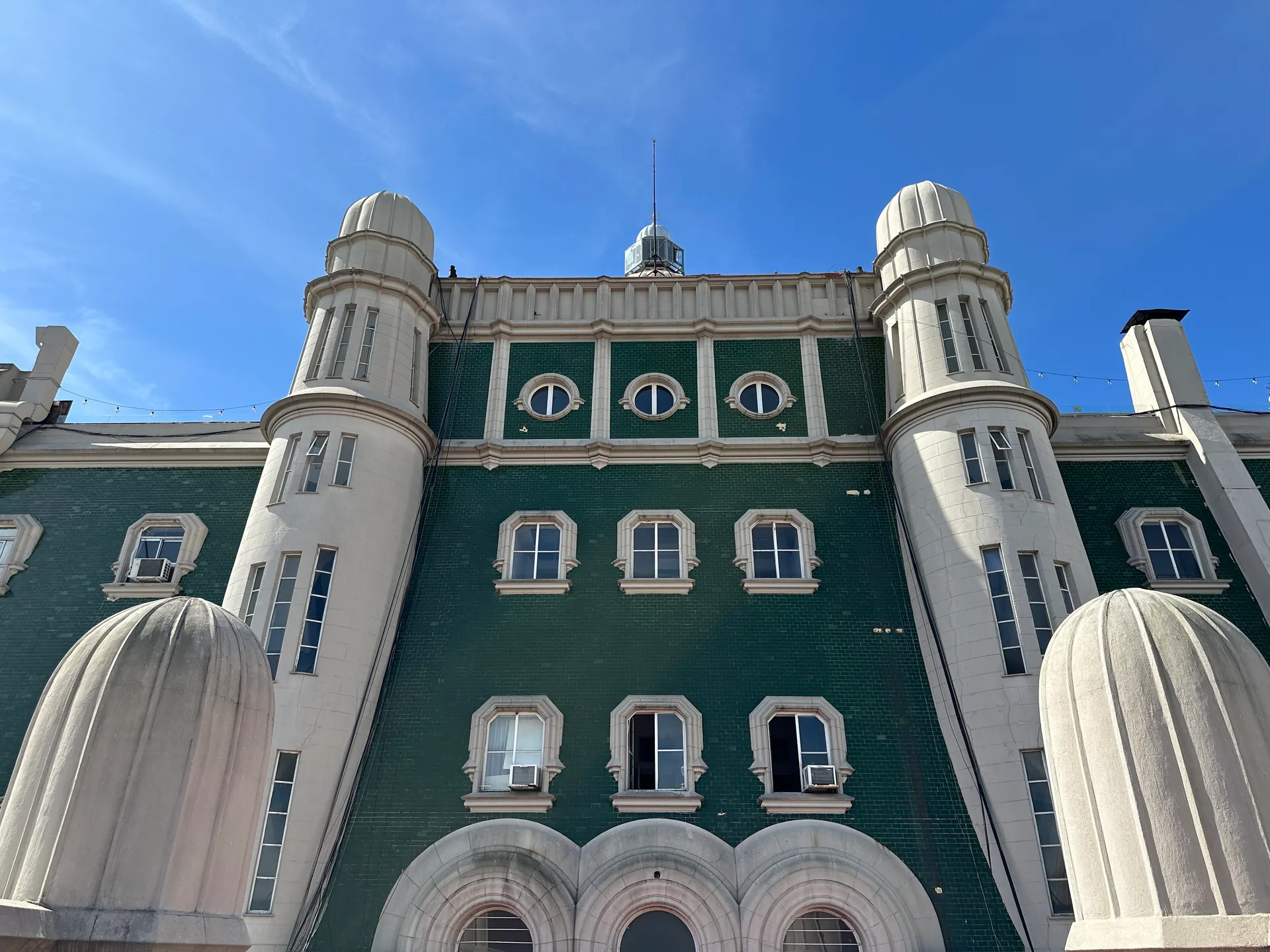 The green-tiled upper facade and white turrets of Palacio Barolo from its terrace.
