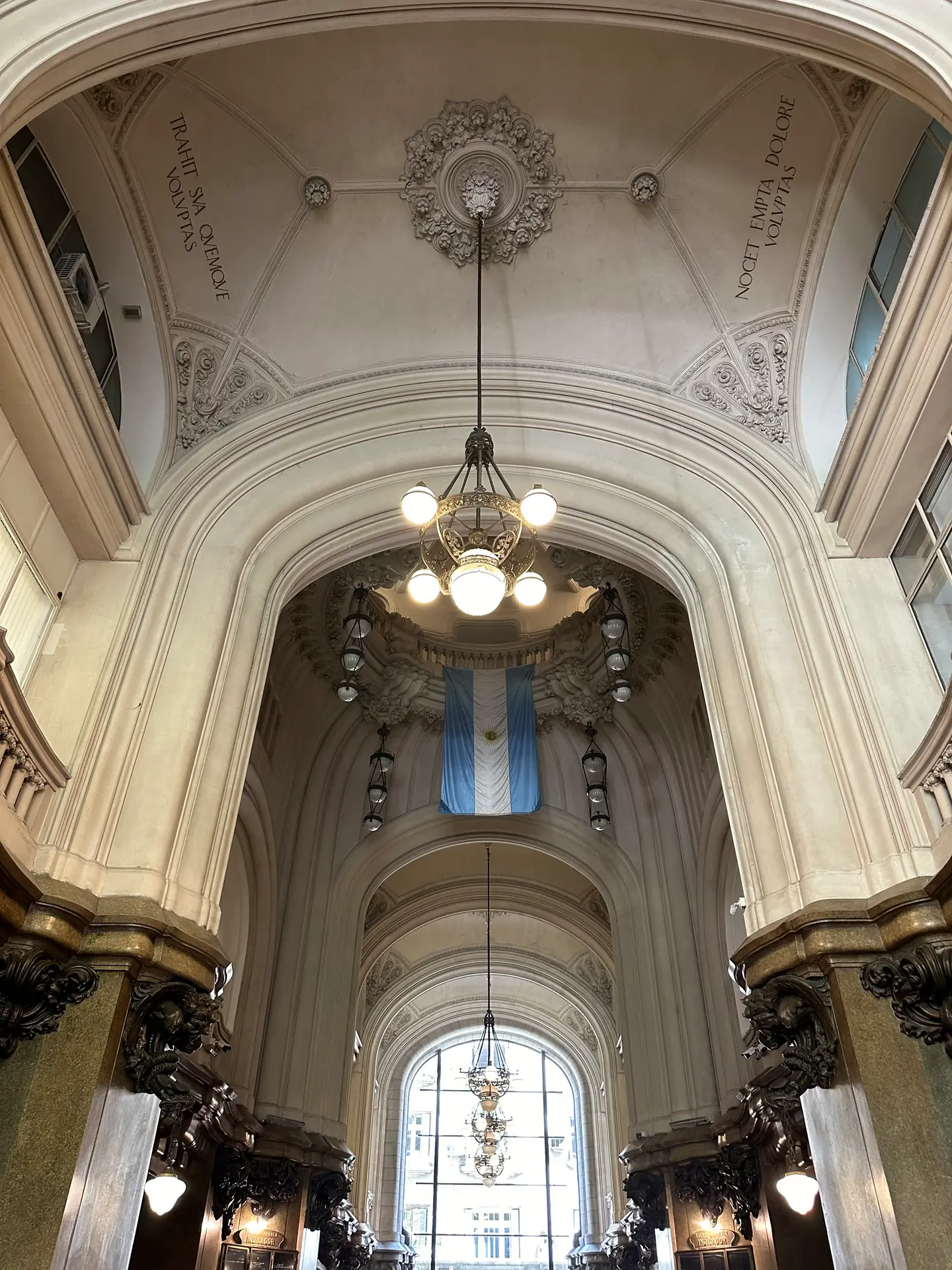The vaulted entrance hall of Palacio Barolo with a chandelier and an Argentine flag.