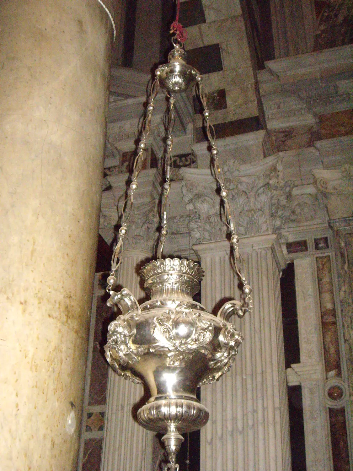 A large silver censer hanging on its chain in the nave of Pisa cathedral