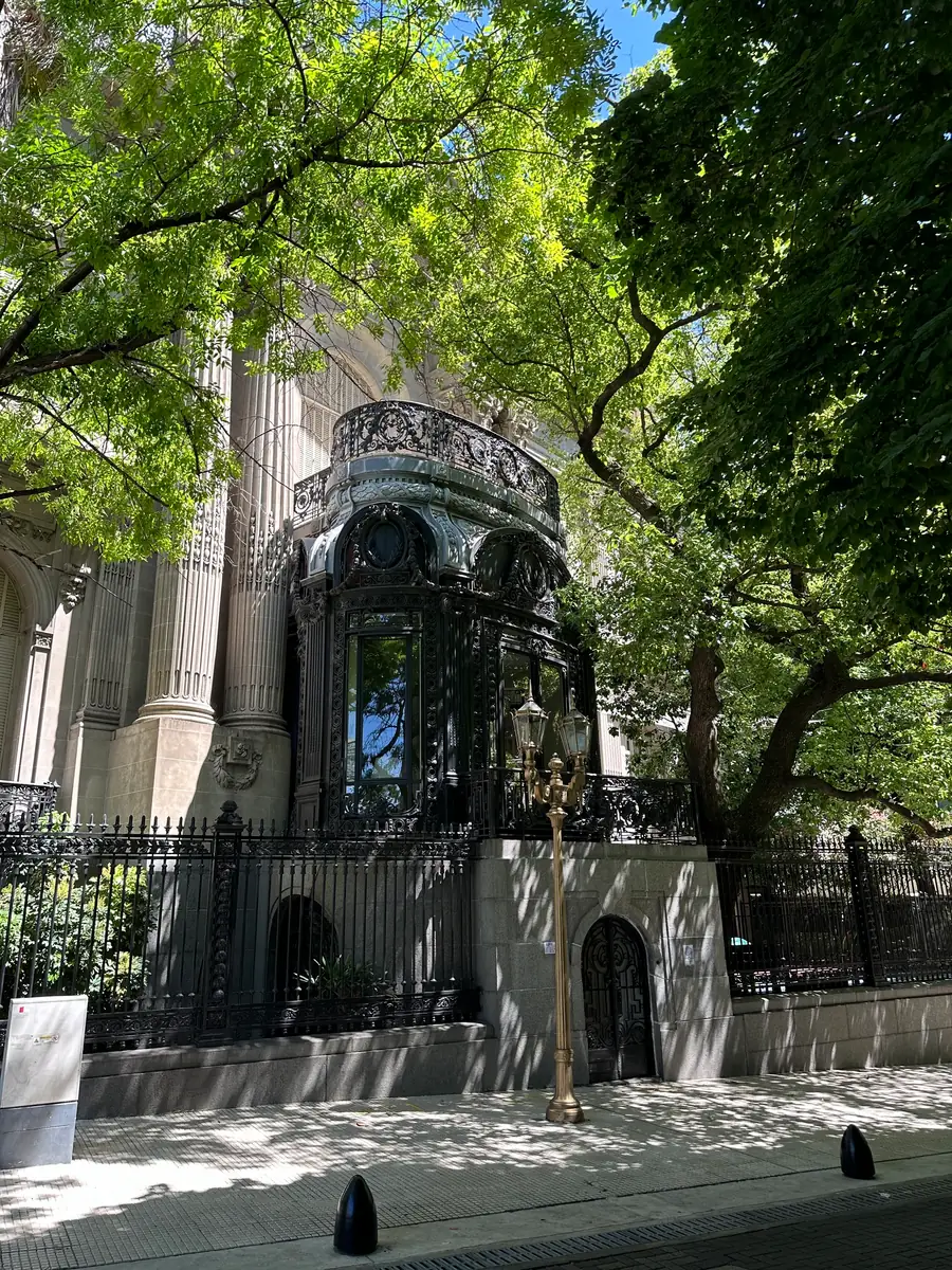 An ornate art nouveau iron entrance canopy behind railings at the Palacio San Martin.