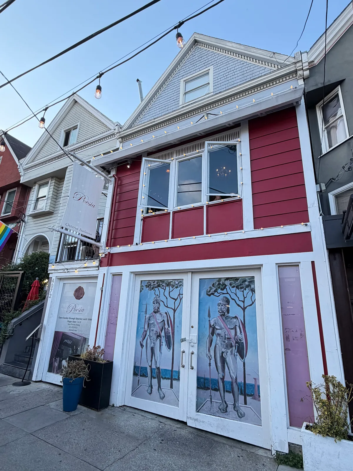 The Poesia storefront, a red Victorian with painted double doors of two classical figures and a Poesia sign.