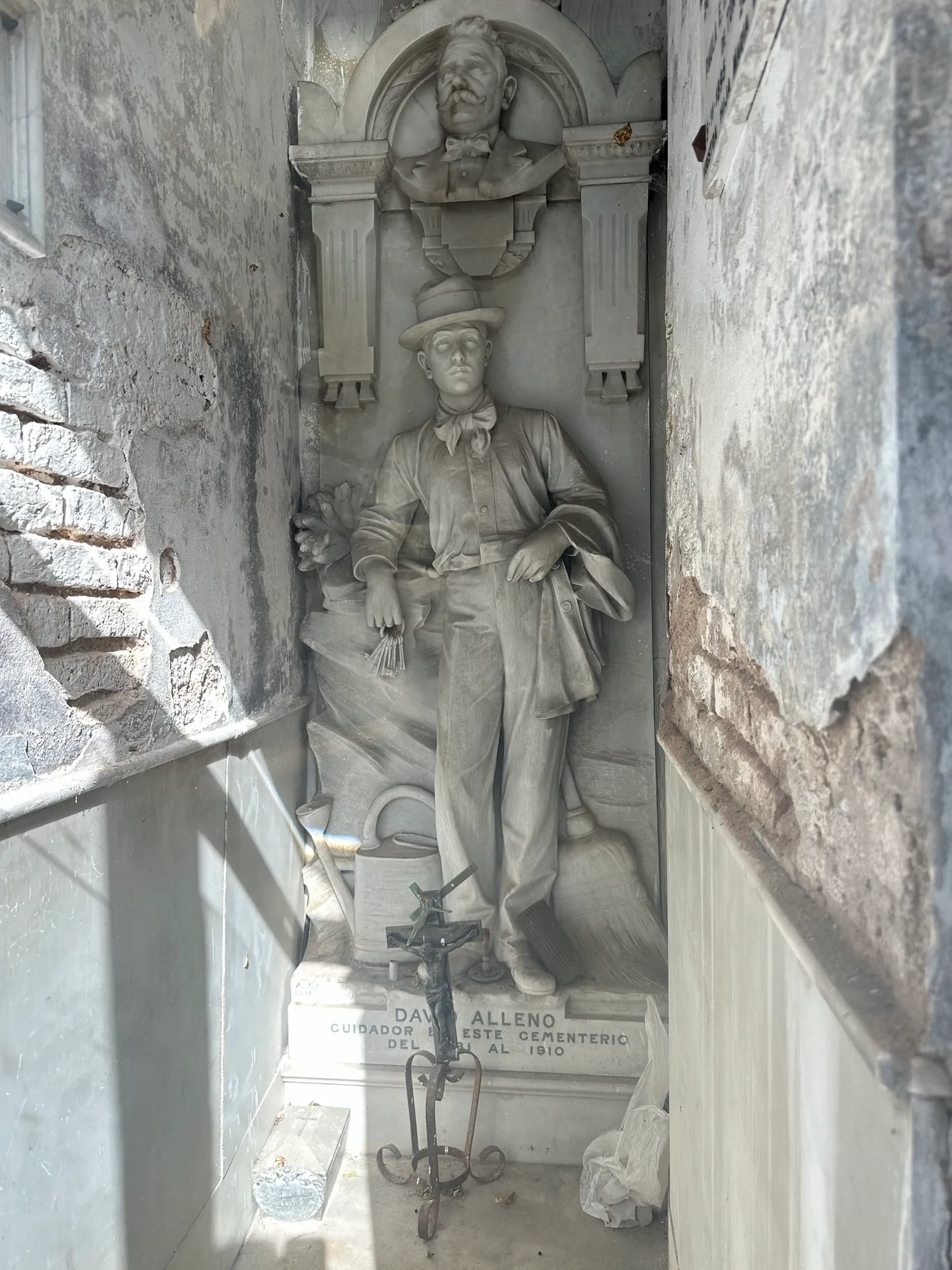 The marble statue of David Alleno in working clothes with keys, a watering can and a broom.