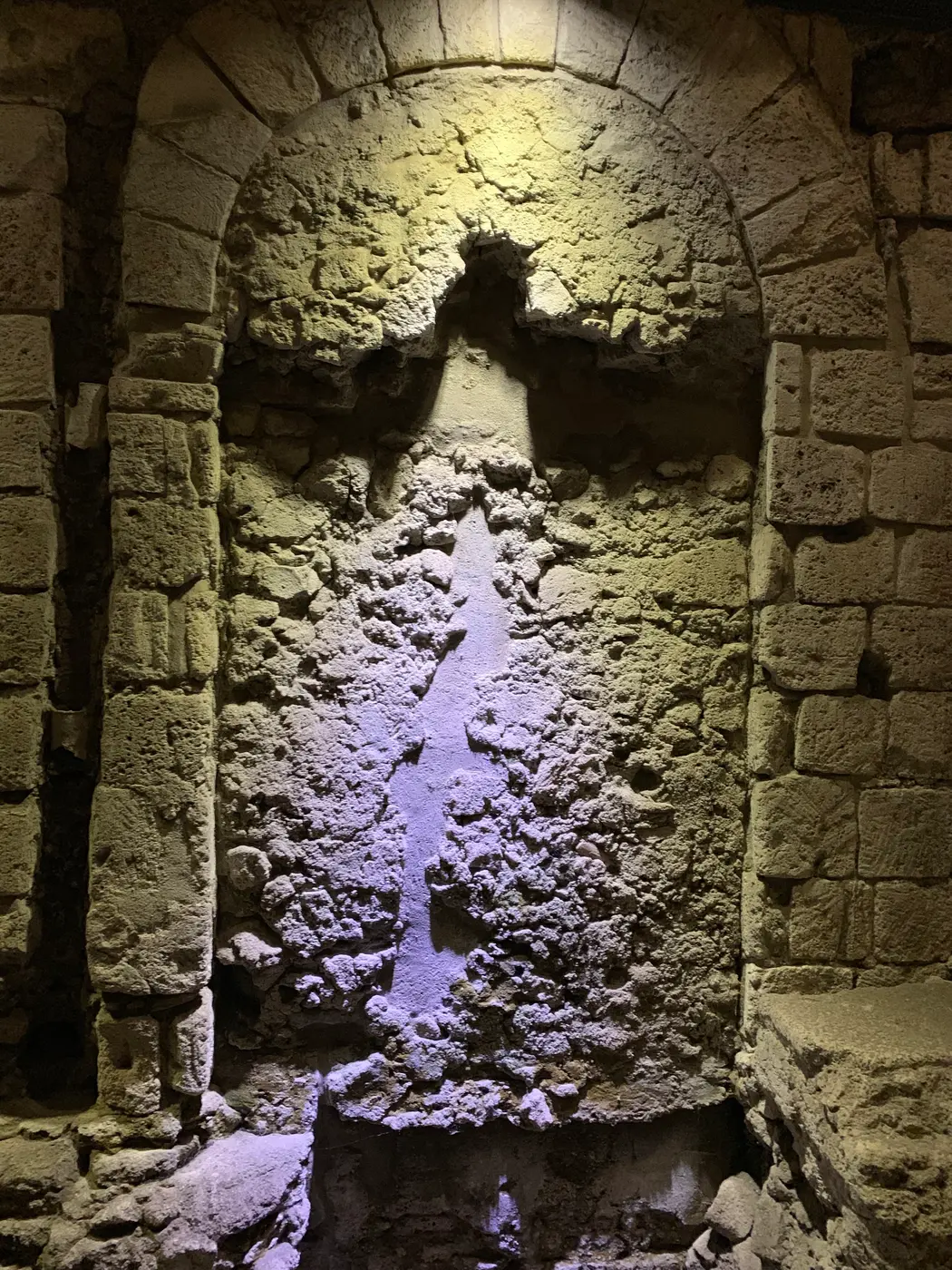 A deep arched stone recess dramatically lit from below in the Naples excavations.