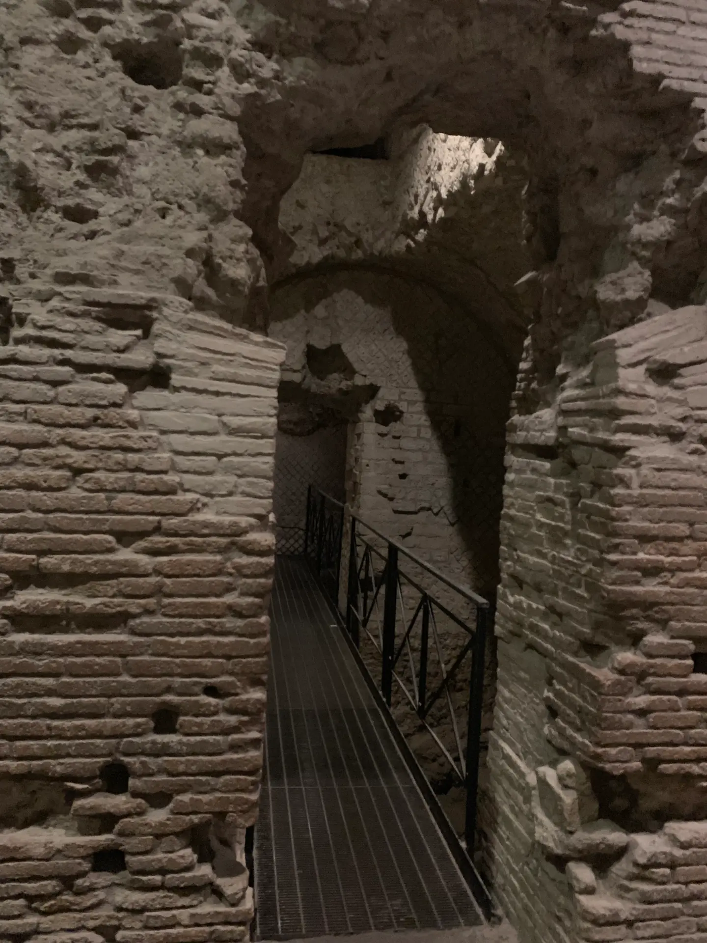 A modern metal stair descending into the lit excavations beneath San Lorenzo Maggiore.