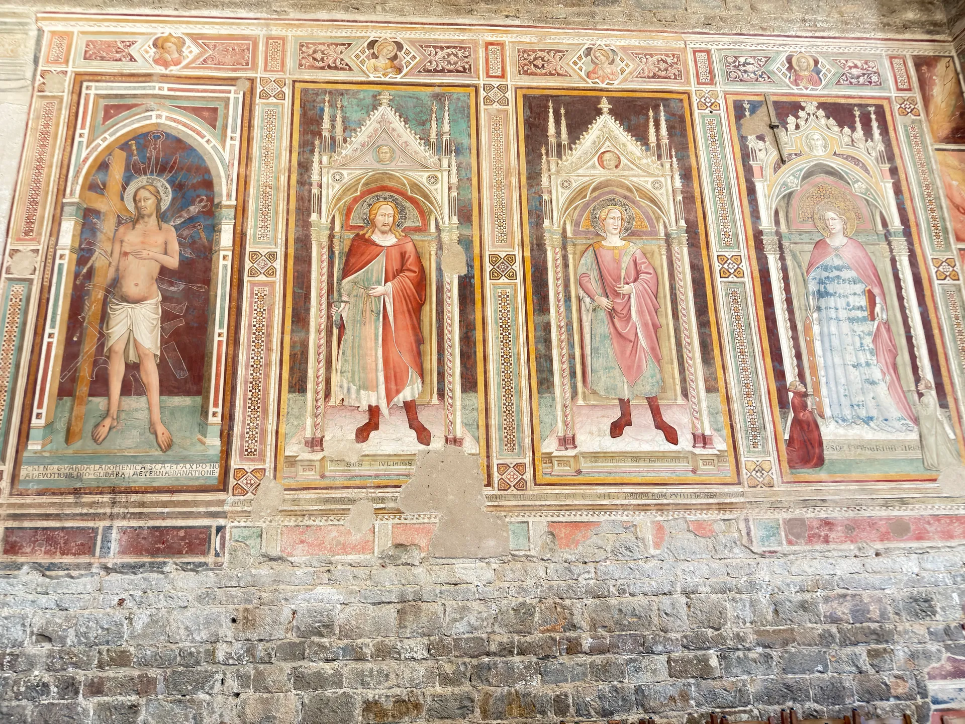 Votive frescoes in painted tabernacles along an aisle wall of San Miniato.