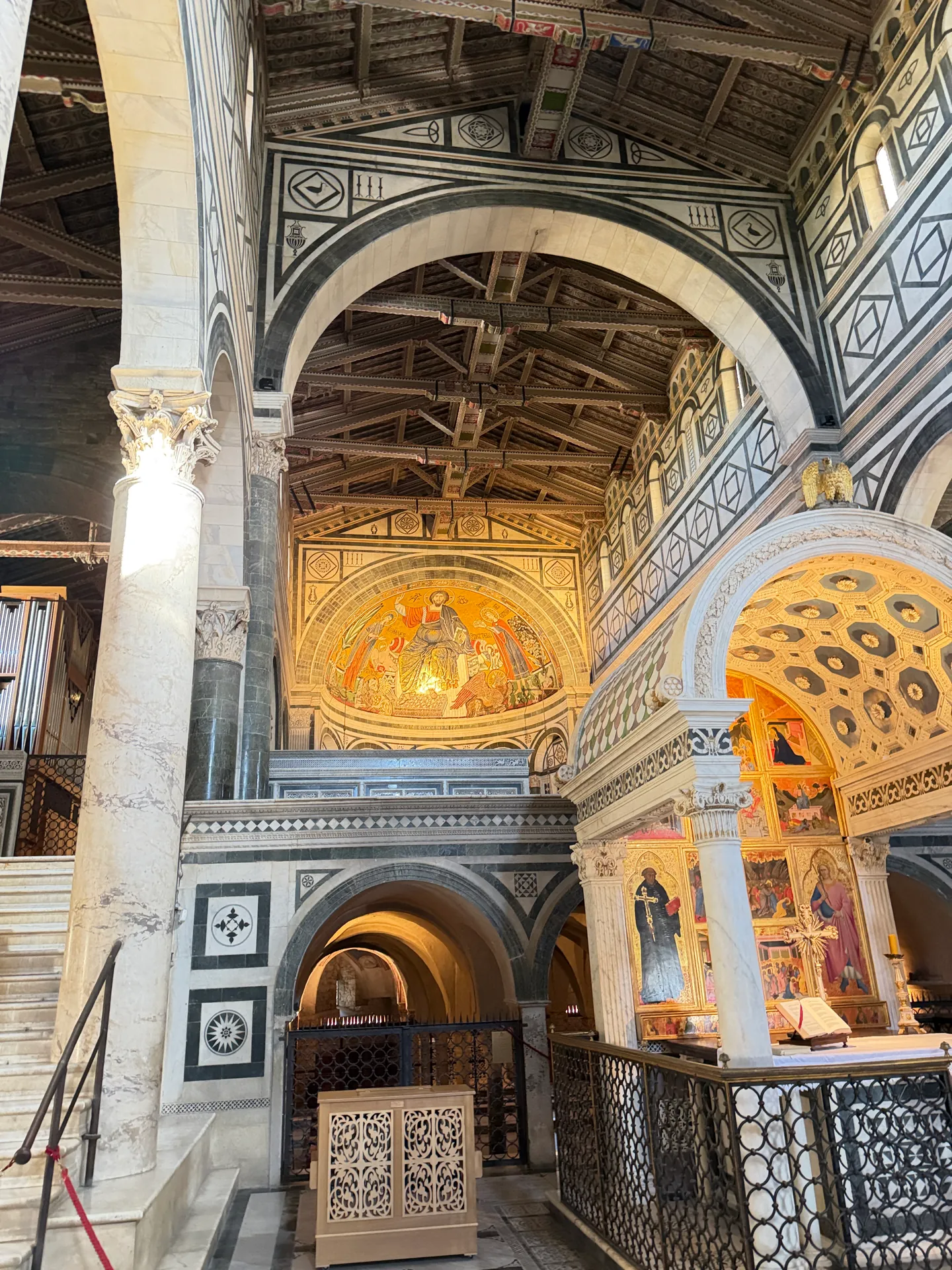 The gold apse mosaic of San Miniato above the inlaid marble parapet of the raised choir, the crypt arches below.
