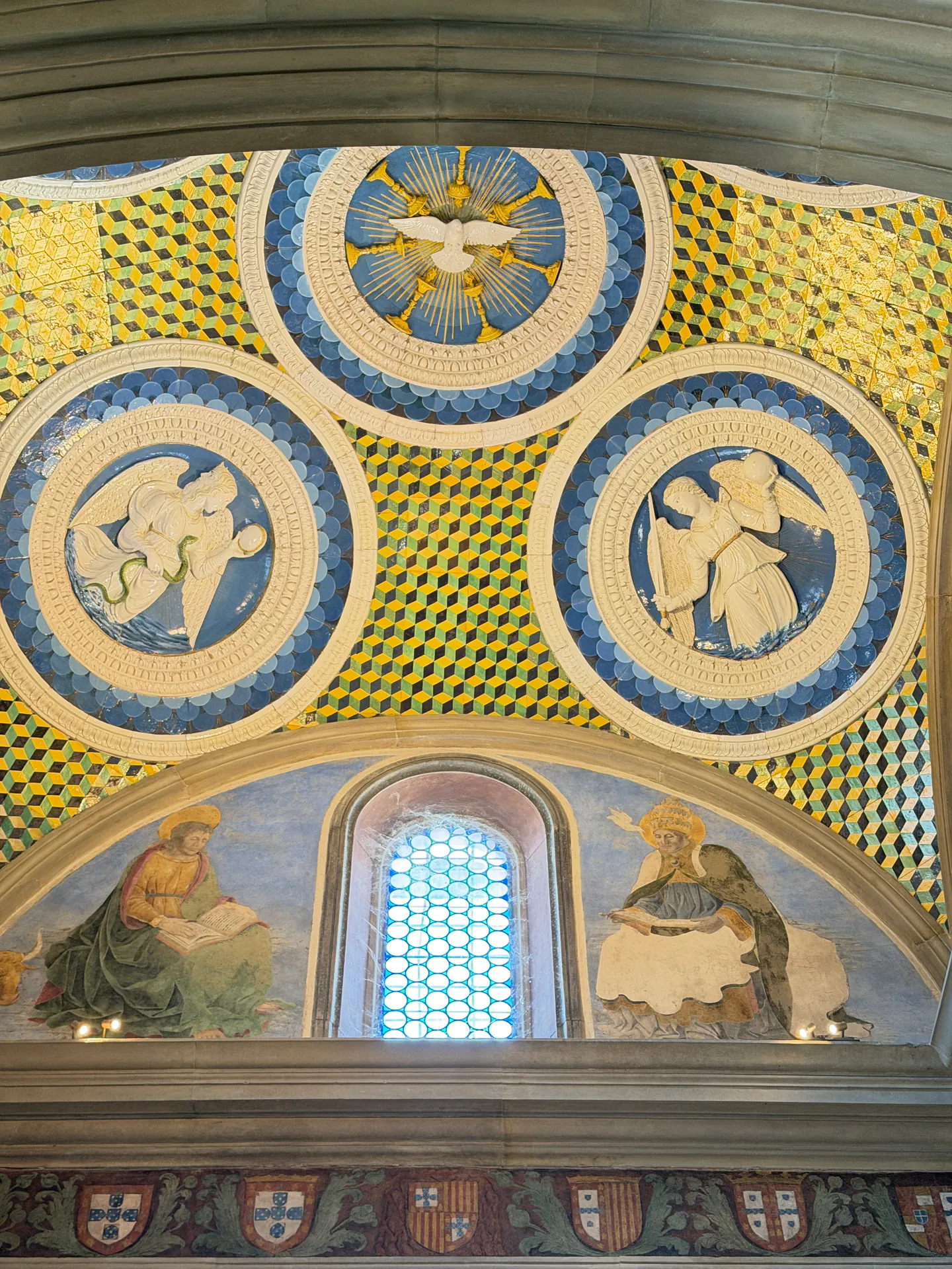 The glazed terracotta ceiling of the Cardinal of Portugal's chapel, a dove roundel among tondi of the Virtues.
